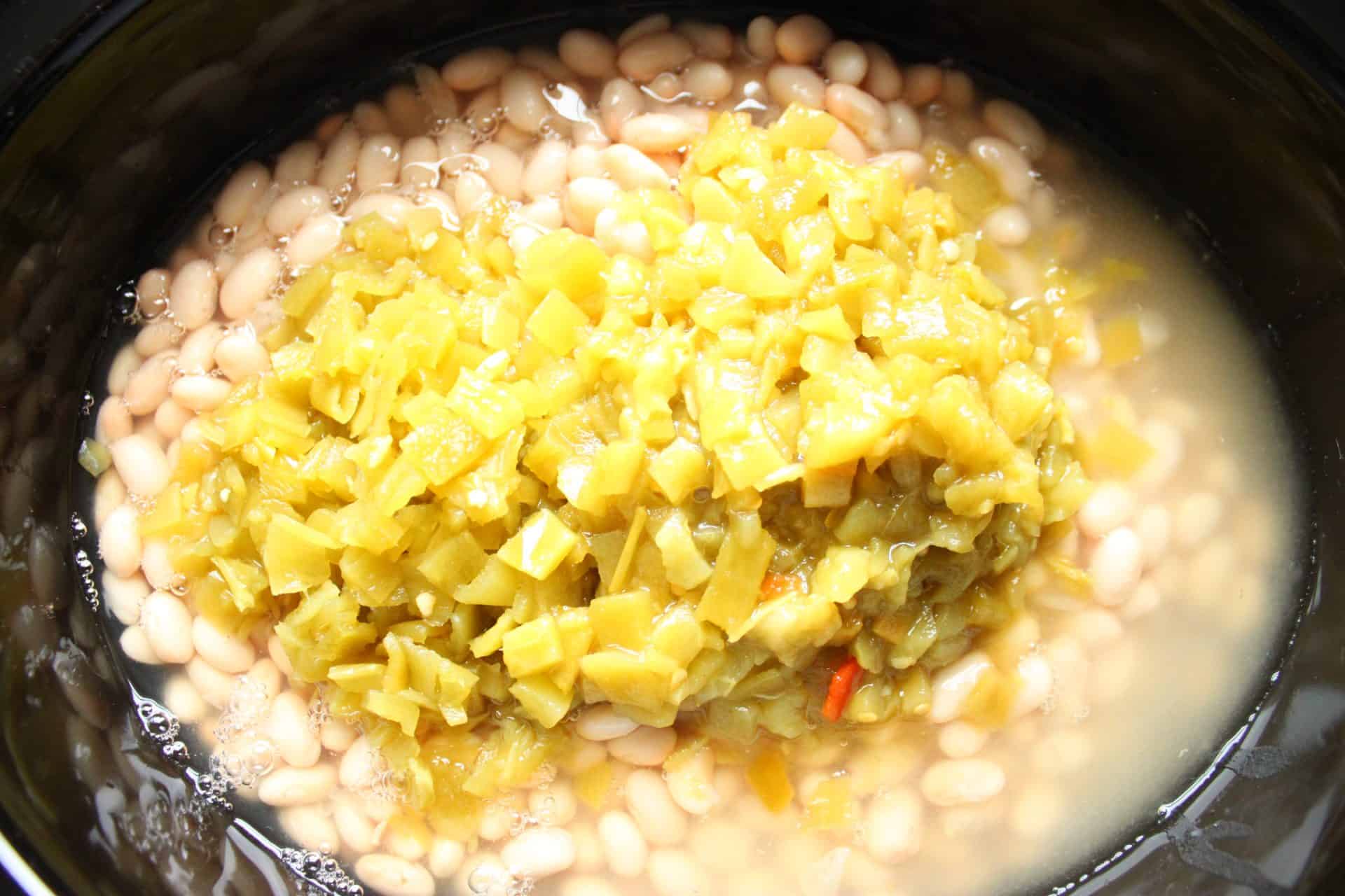 Chopped green chiles and white beans added to the slow cooker, bringing hearty flavor to Healthy Crockpot White Chicken Chili.