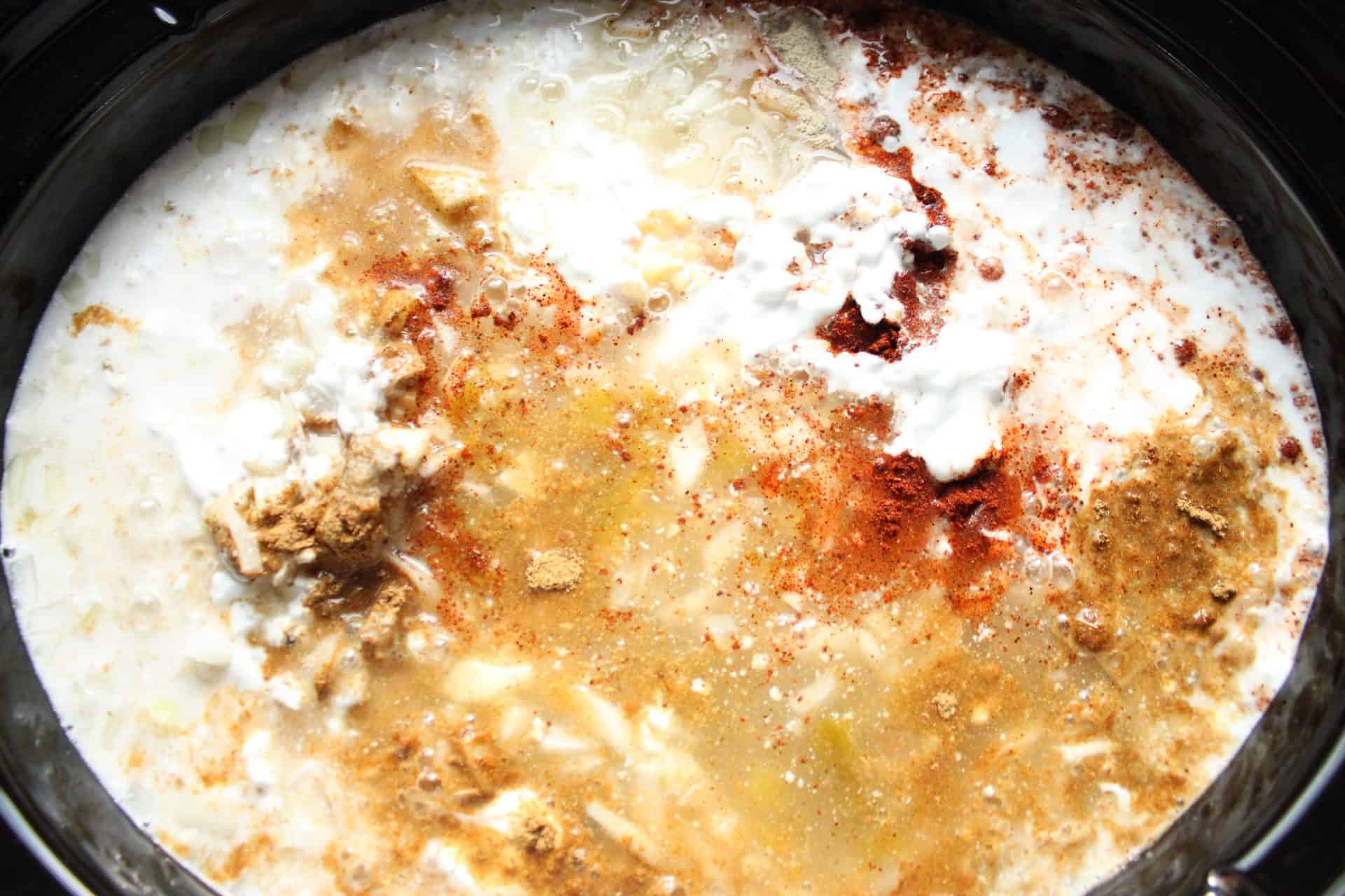 Coconut milk and spices poured into the slow cooker, giving the Healthy Crockpot White Chicken Chili a creamy, flavorful base.