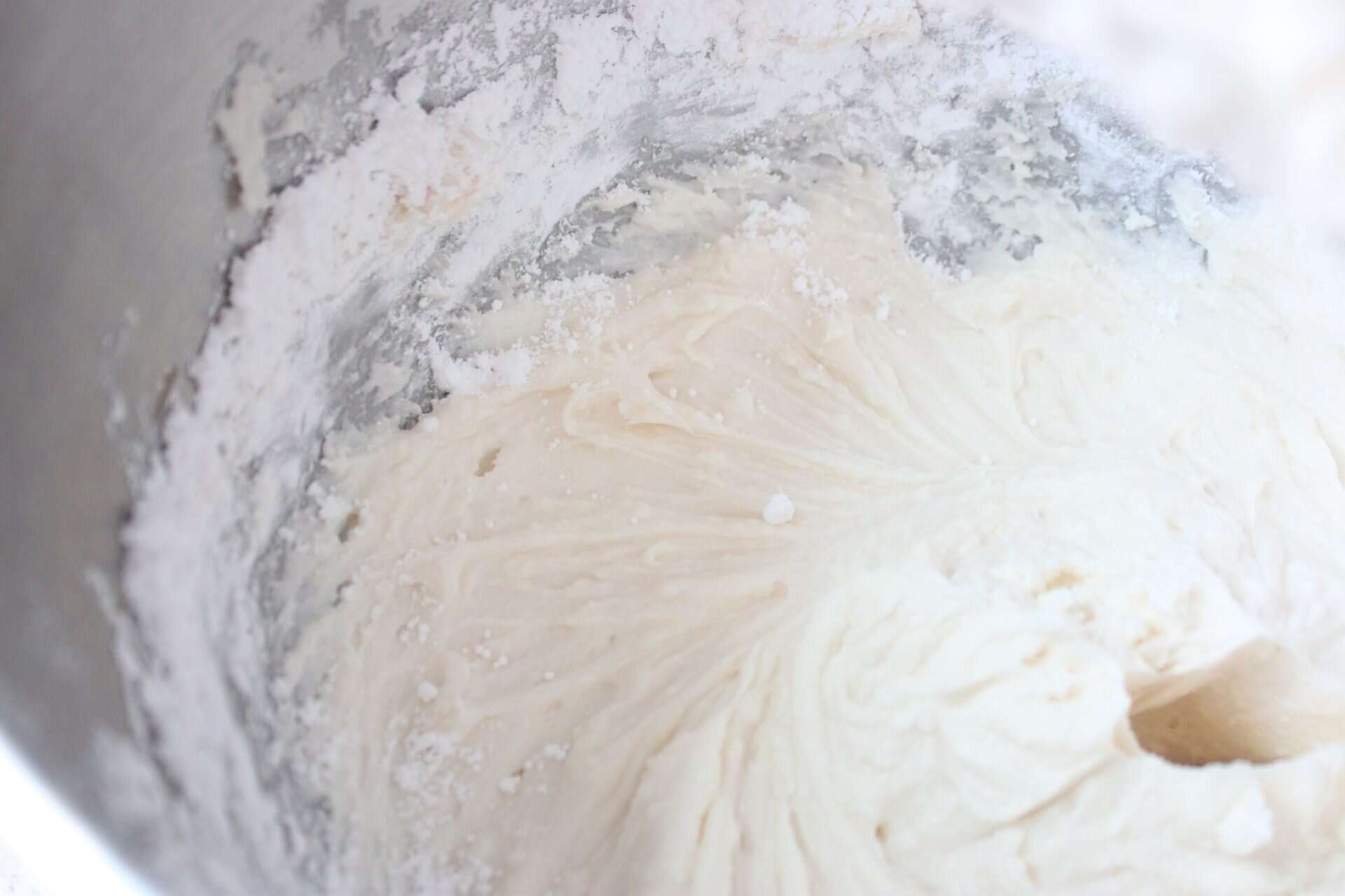 Adding Powdered Sugar to Buttercream Mixture in the Bottom of Stainless Mixer Bowl