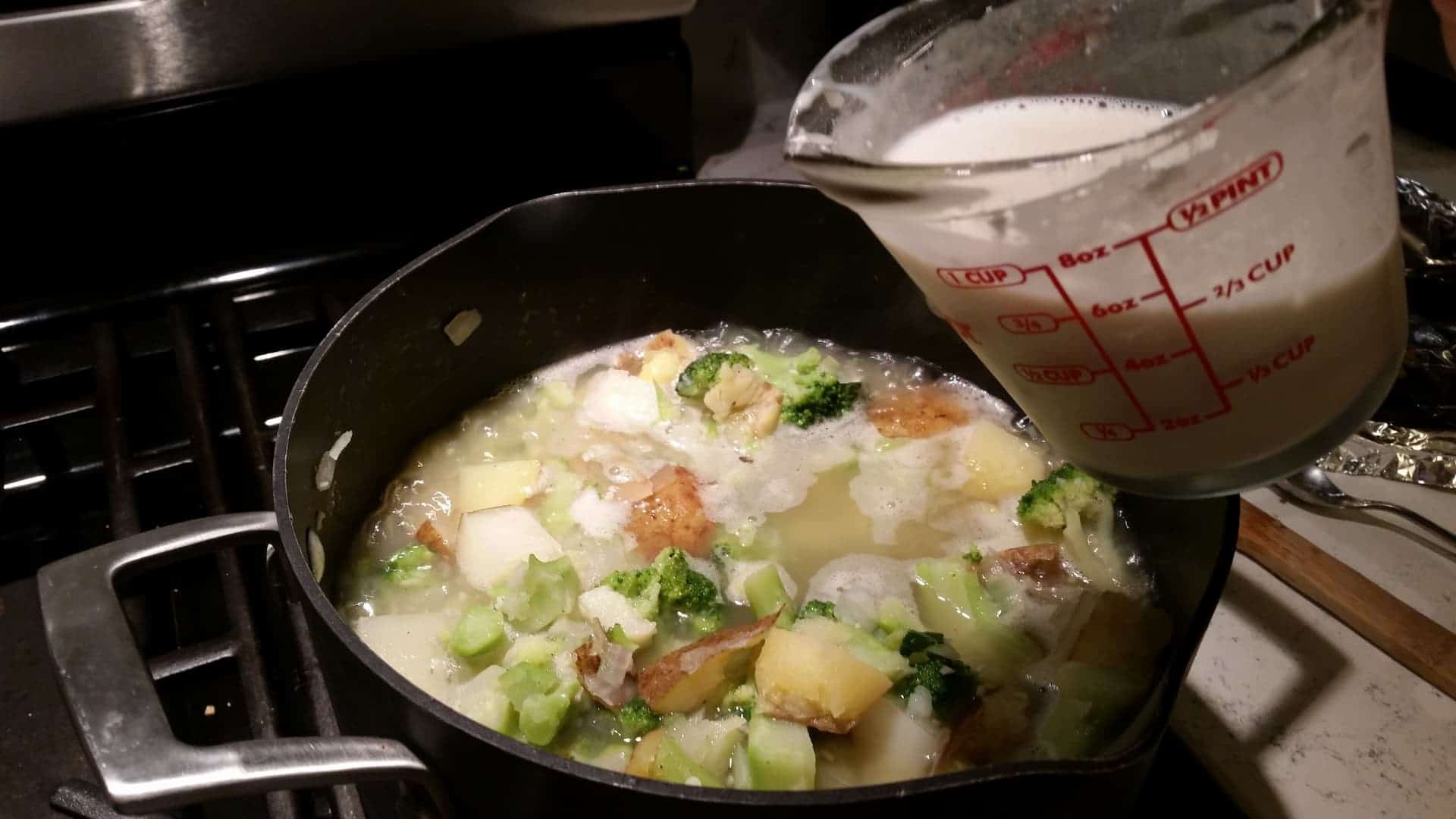 Adding Whisked Non Fat Milk and Flour Mixture to Soup Ingredients in a Black Stock Pot