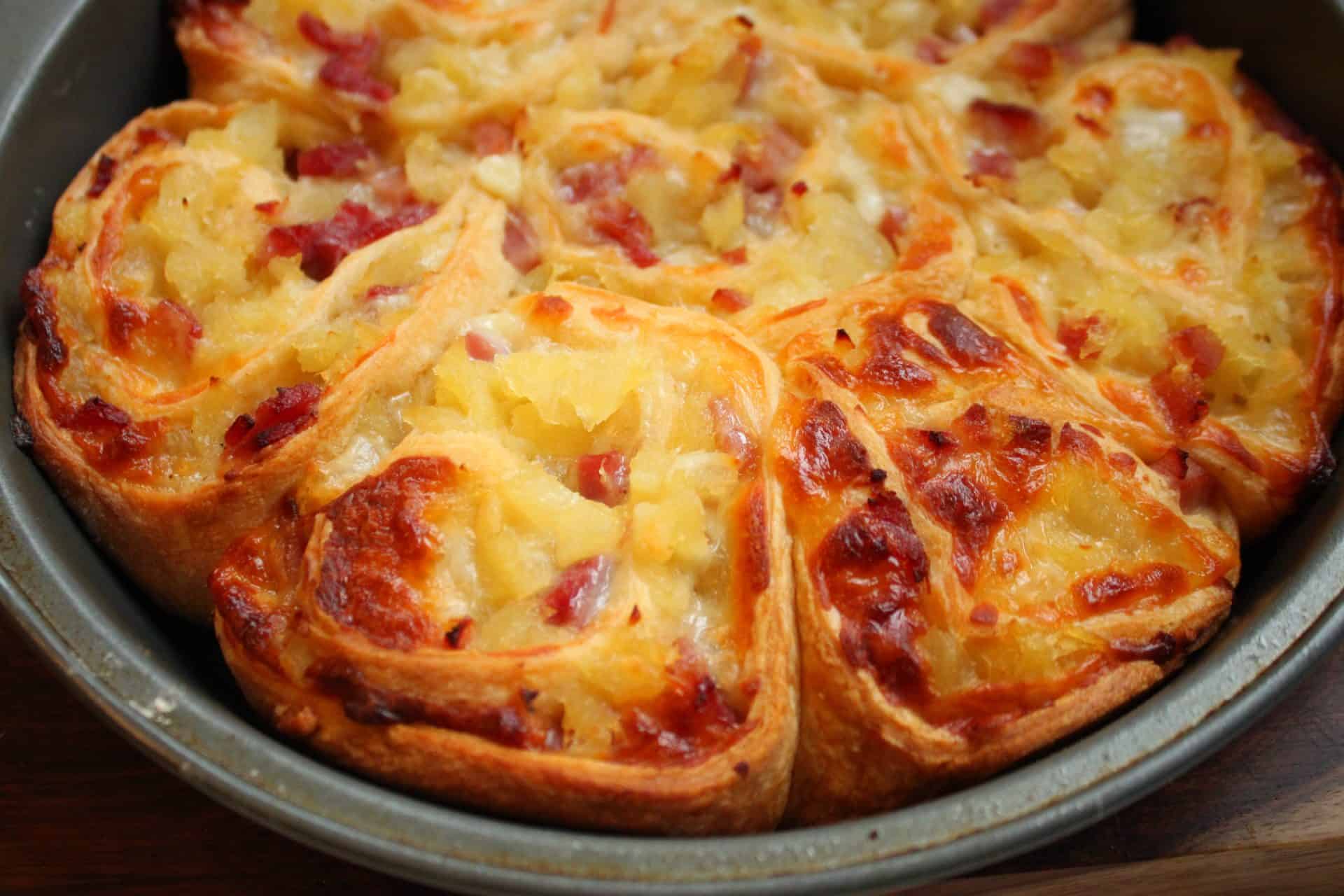 Savory and Sweet Ham and Pineapple Pinwheels for the Family 6 A close-up of freshly baked ham and pineapple pinwheels, golden brown with melted cheese and pineapple pieces on top.