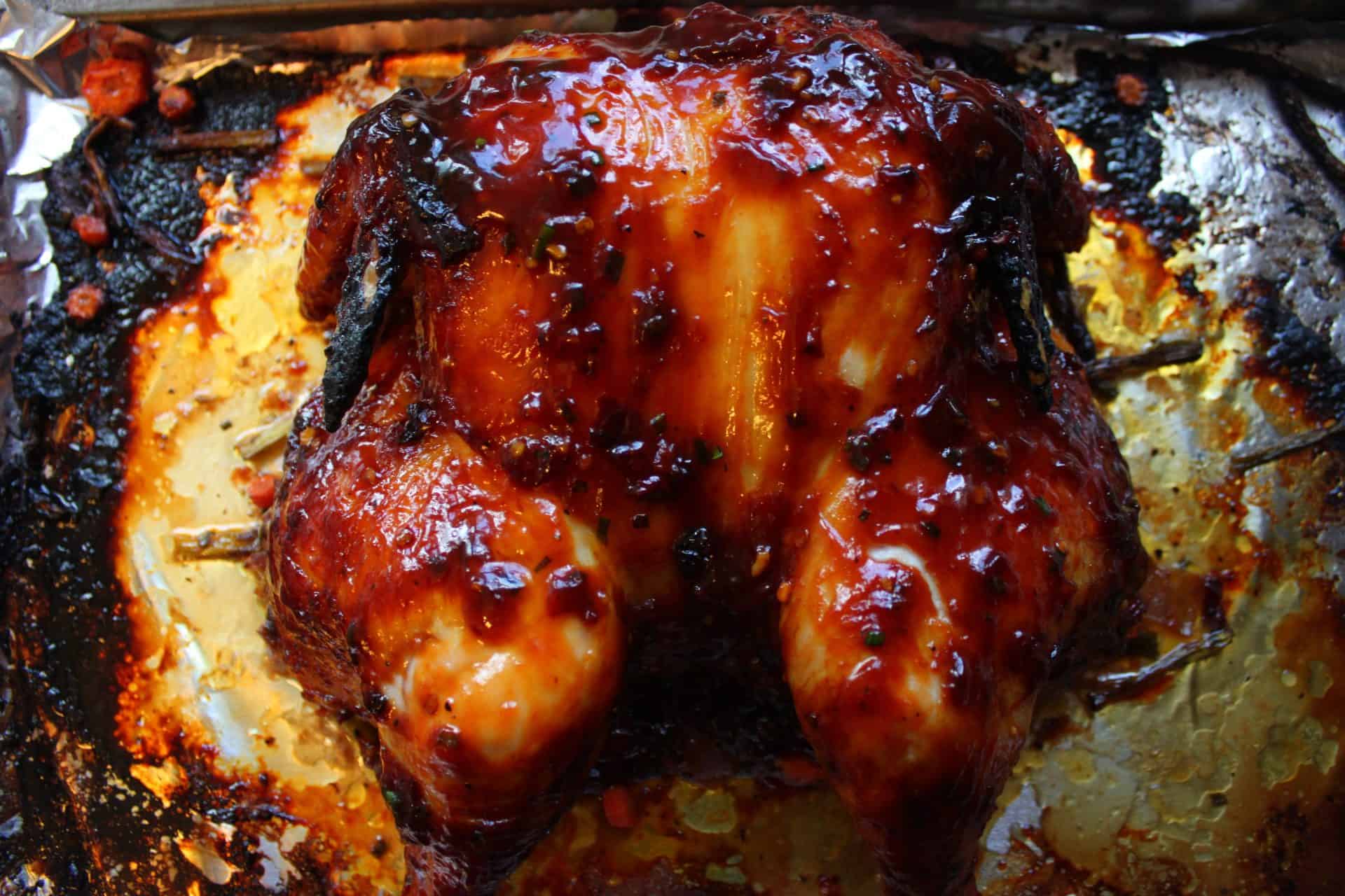 Golden brown, baked spatchcock chicken fresh out of the oven, coated in sticky BBQ sauce with a crispy, caramelized skin.