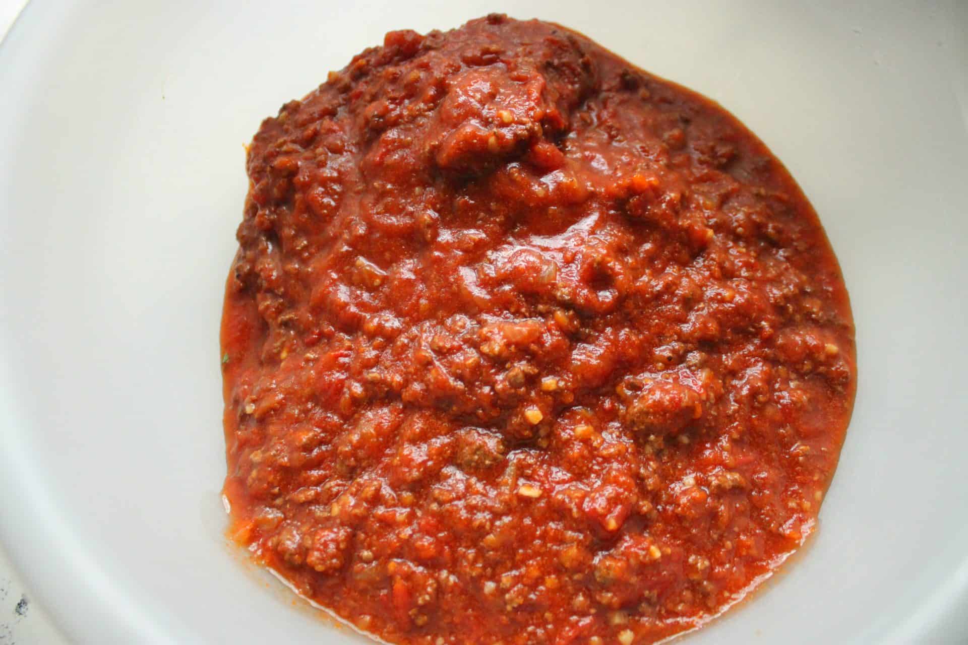 A bowl of homemade bolognese sauce, rich and thick, ready to be mixed into freezer-friendly cheesy baked ziti.