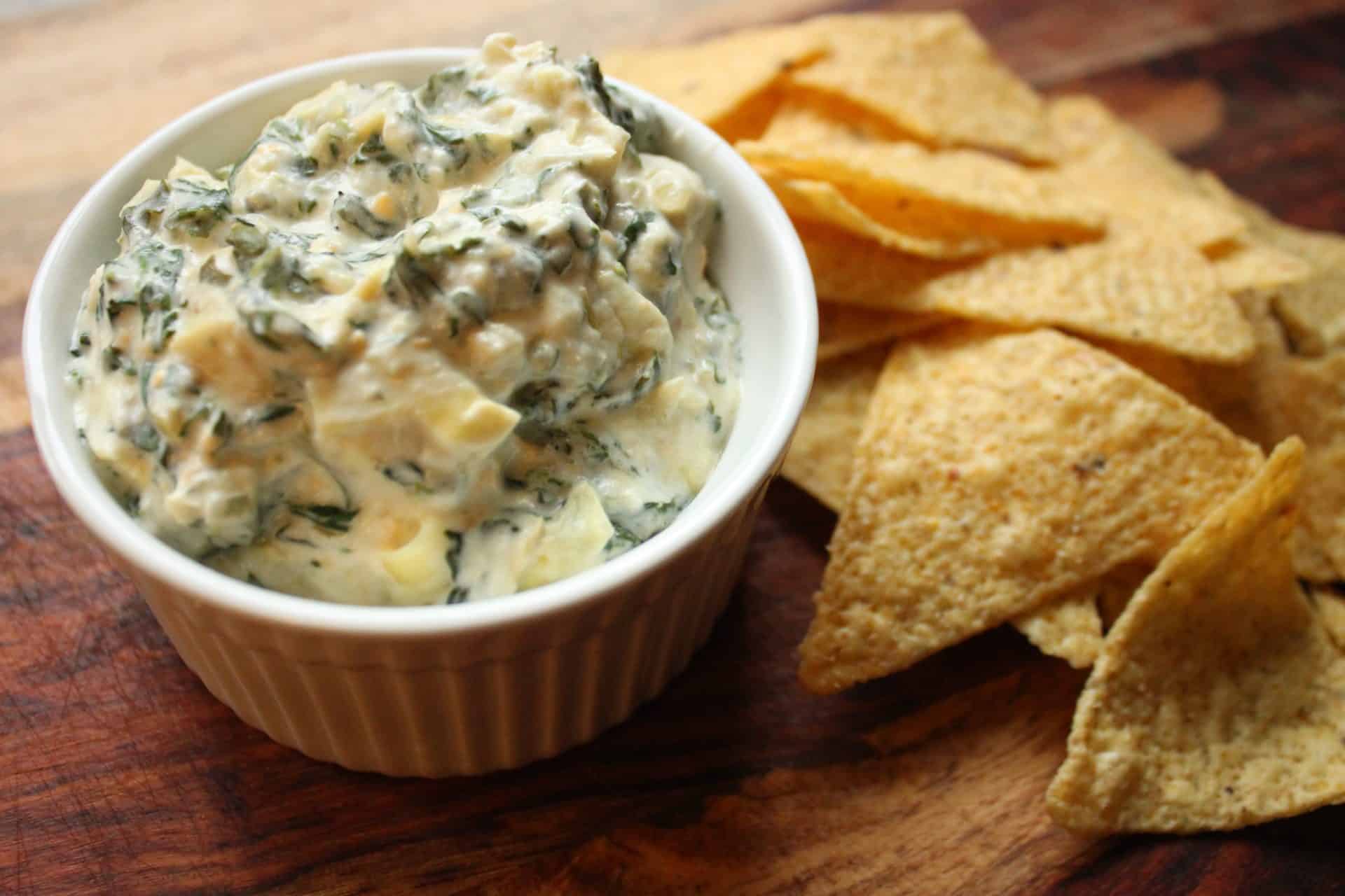 This Crockpot Spinach Artichoke Dip Will Be Your Next Party Hit 4 Bowl of warm, cheesy Crockpot Spinach Artichoke Dip served with crispy tortilla chips on the side for easy dipping.