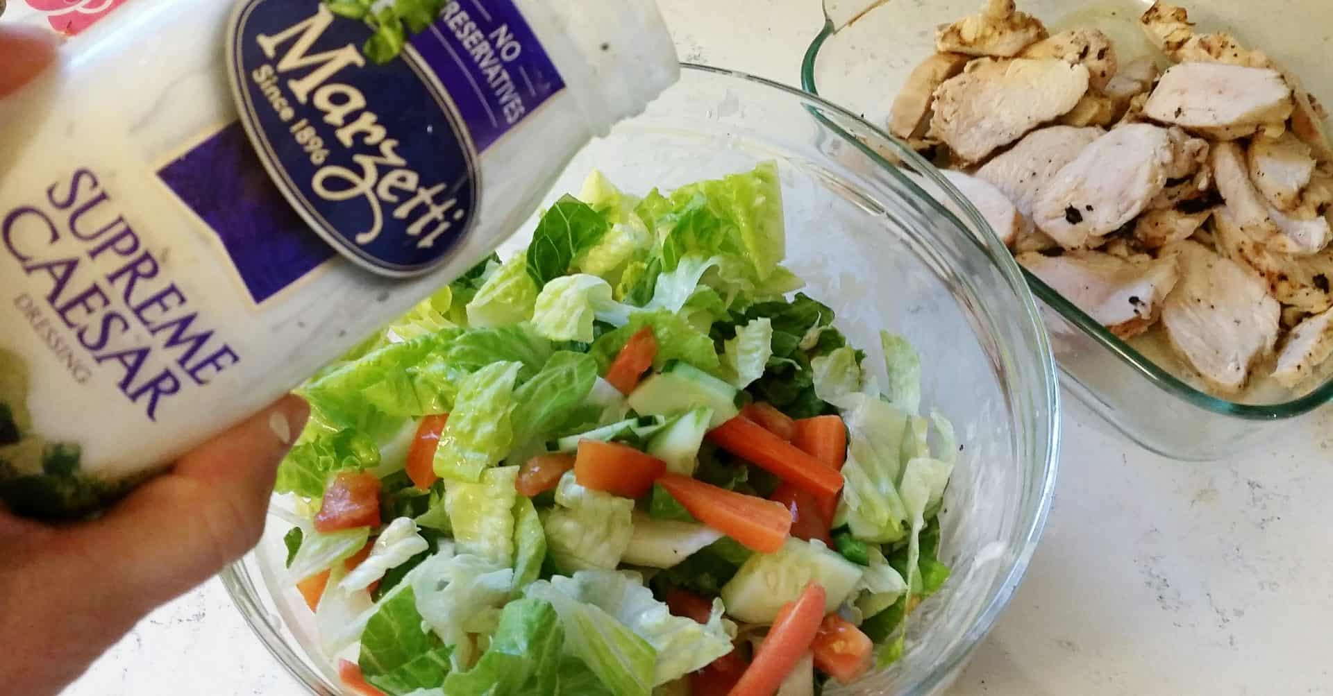 Caesar Salad Dressing Being Poured over a Bowl of Salad