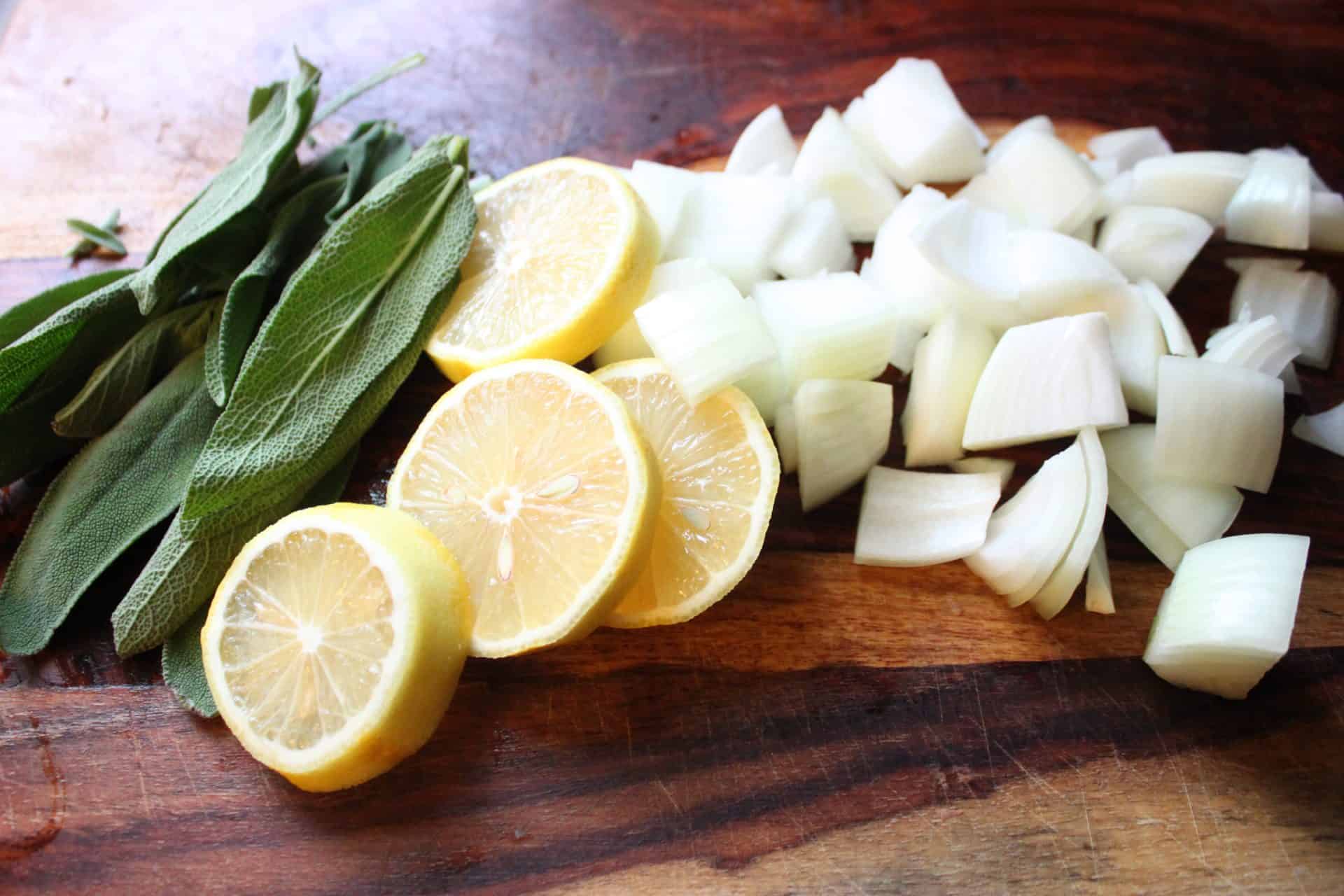 Foolproof 3-Step Tuscan-Style Roasted Turkey for the Holidays 3 Sliced lemon, sage leaves, and diced onions on a cutting board, aromatic ingredients for Tuscan-style roasted turkey stuffing.