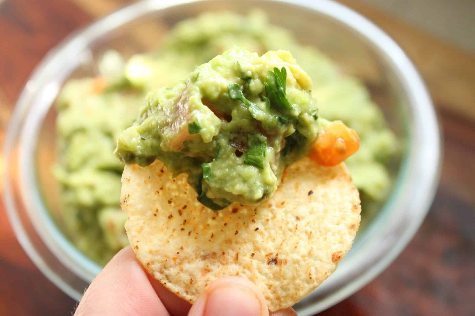 Chunky Restaurant Style Guacamole Recipe Scooped onta a Tortilla Chip