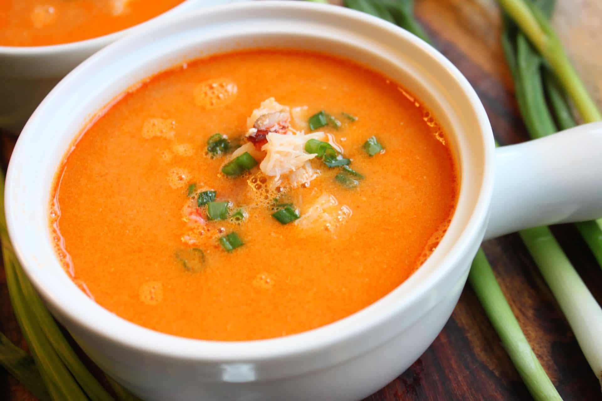 Closeup of a bowl of 30 Minute Dungeness Crab Bisque Recipe topped with crab meat and chives, highlighting the smooth, rich consistency.