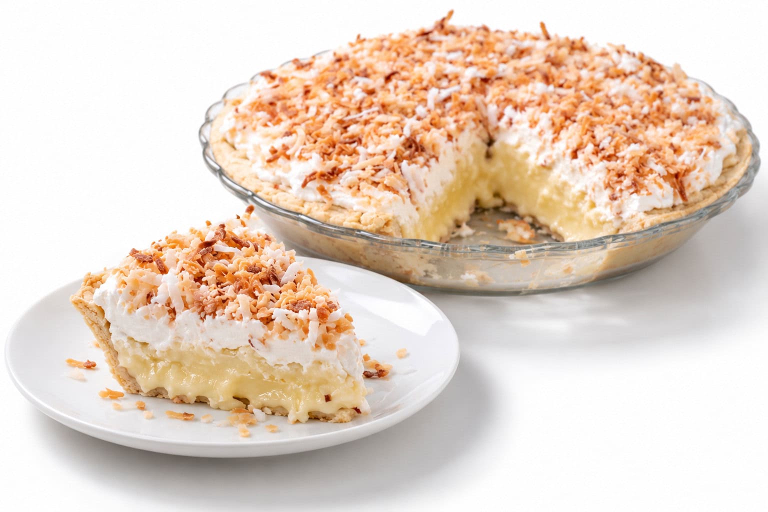 Slice of coconut cream pie showing creamy filling and soft topping, with the whole pie behind it missing one slice.