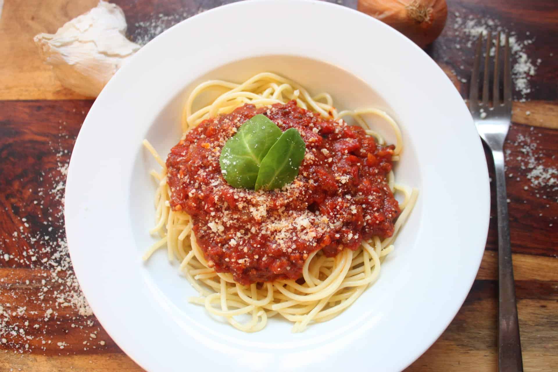 White Bowl Fillled withCrockpot Spaghetti Bolognese Sauce over Noodles