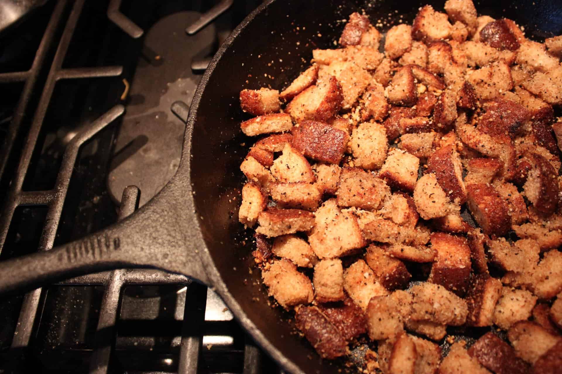 Parmesan Croutons Cooking in a Black Cast Iron Skillet on the Stove