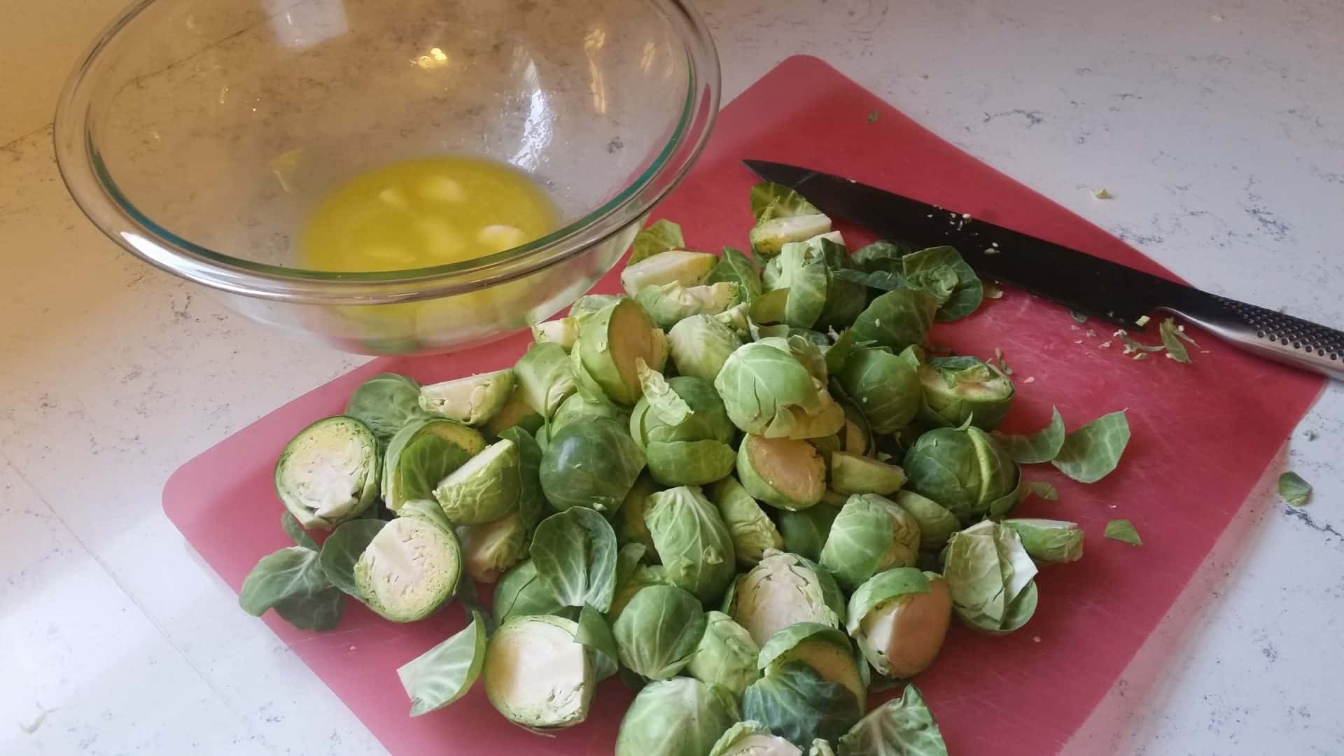 Cutting up the Brussel Sprouts on a Cutting Board with a Chefs Knife