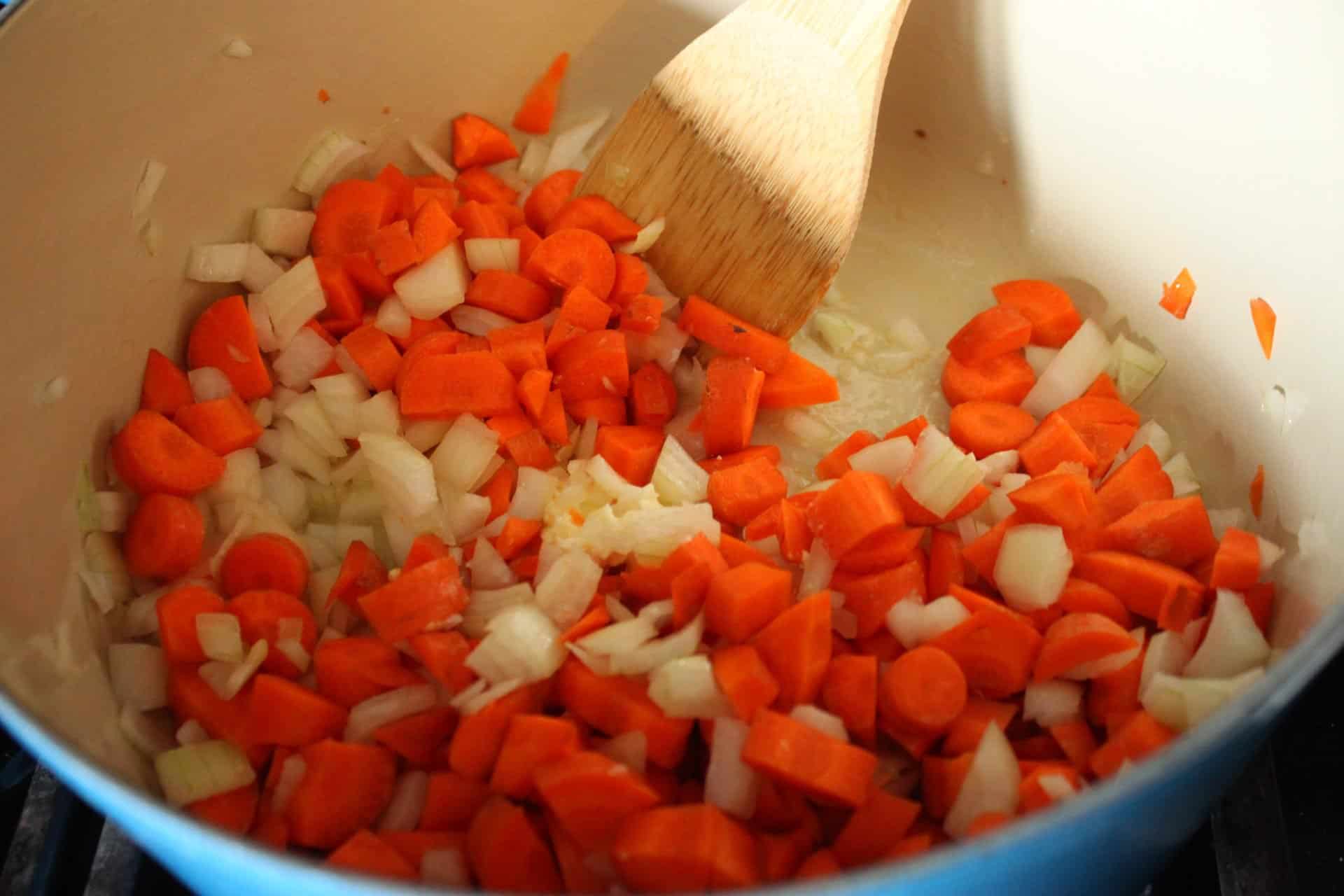 Revamp Easter Leftovers with Ham Spinach Cannellini Bean Soup 1 Diced Onions and Carrots in a Blue Dutch Oven