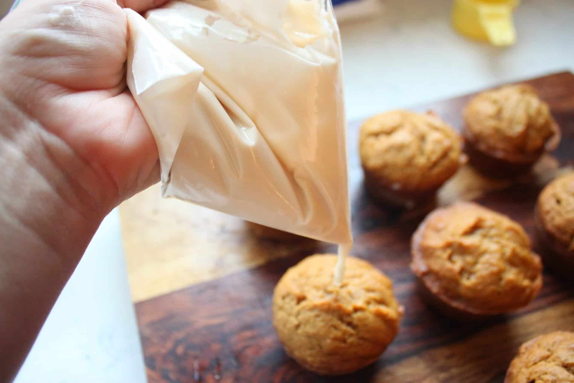 Drizzling Vanilla Frosting from a Zip Lock Bag on Pumpkin Muffins