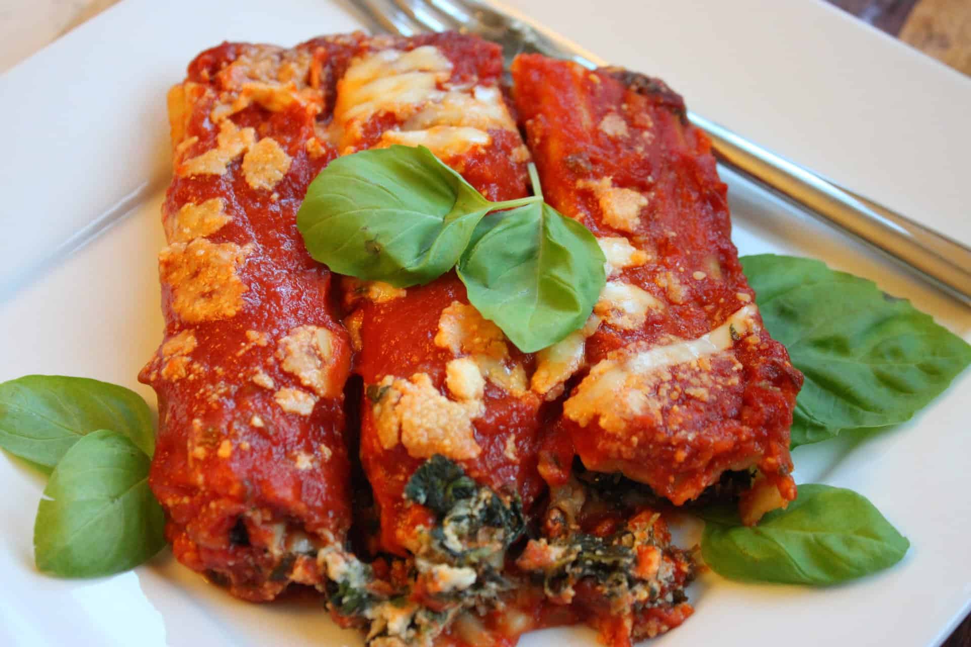 Freezer-Friendly Spinach Manicotti on Plate Topped with a Basil Leaf