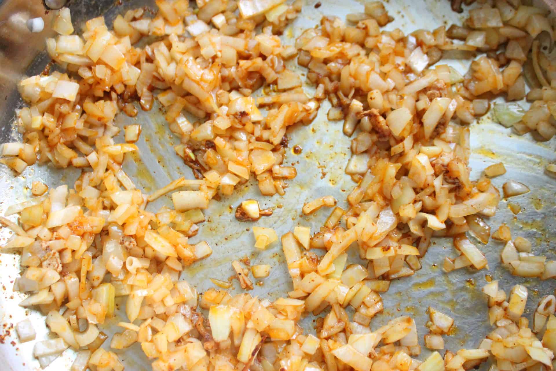 How to Make Flavor-Packed Green Chile Chicken Enchiladas at Home 5 Golden brown sautéed onions in a skillet, cooked until caramelized for the filling in green chile chicken enchiladas.