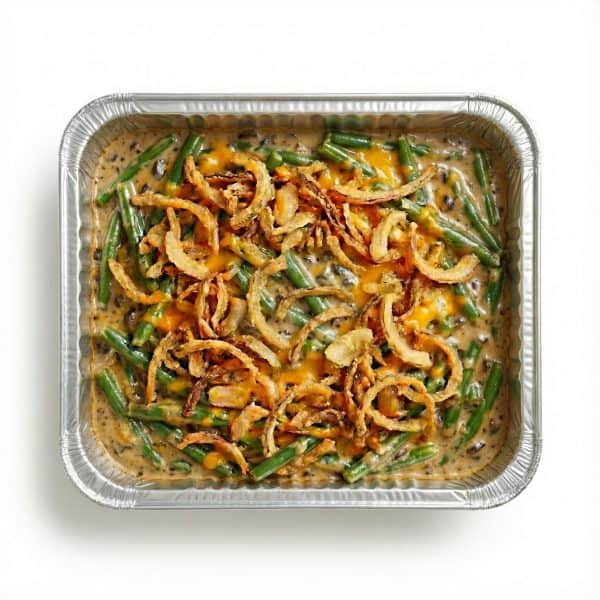 Green Bean Casserole 2 Green bean casserole with mushroom sauce, cheddar cheese, and crispy fried onions in aluminum takeout container