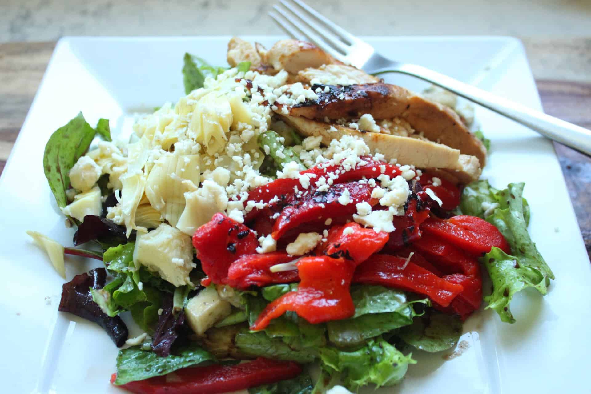 Flavor-Packed 30-Minute Grilled Chicken Artichoke Salad You'll Love 8 Grilled Chicken Artichoke Salad on a Large White Square Plate with a Fork on the Side