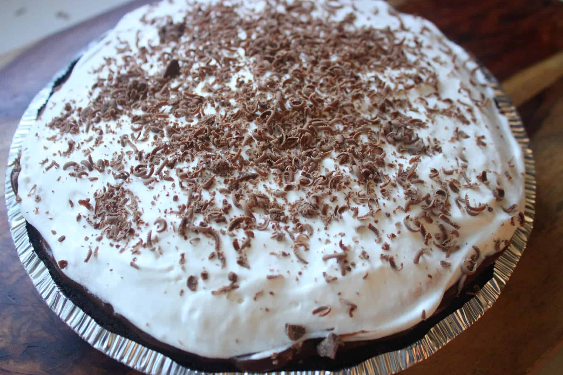 A delicious chocolate cream pie topped with whipped topping and chocolate shavings, perfect for potlucks or family nights.