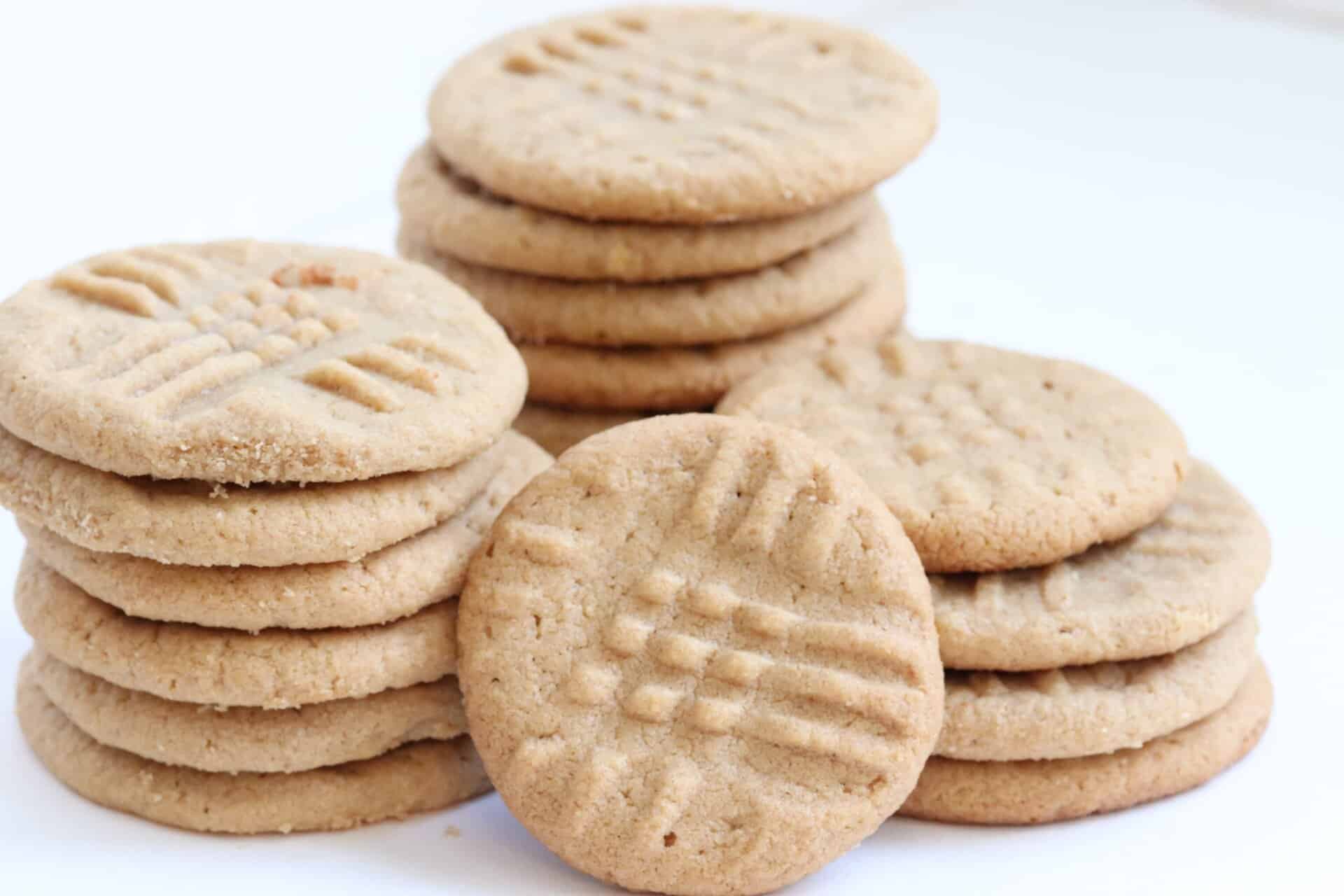 Golden 3 Ingredient Peanut Butter Cookies stacked and arranged in front of a light background, highlighting their soft and chewy texture.