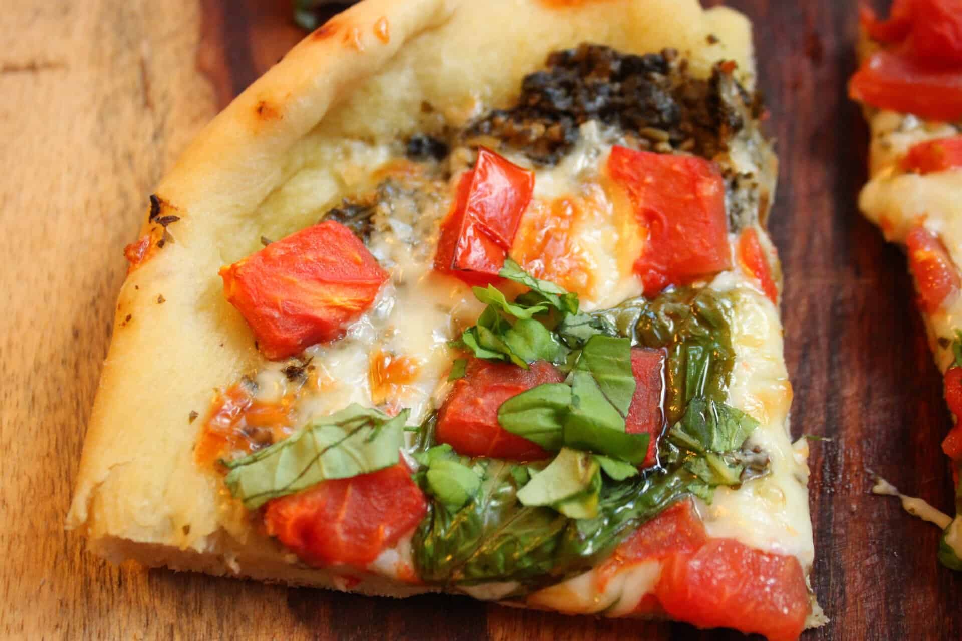 Easy Weeknight Favorite: 5-Ingredient Tomato Pesto Pizza 8 A slice of 5-Ingredient Tomato Pesto Pizza with melted cheese, diced tomatoes, and fresh basil, perfect for weeknight dinners.