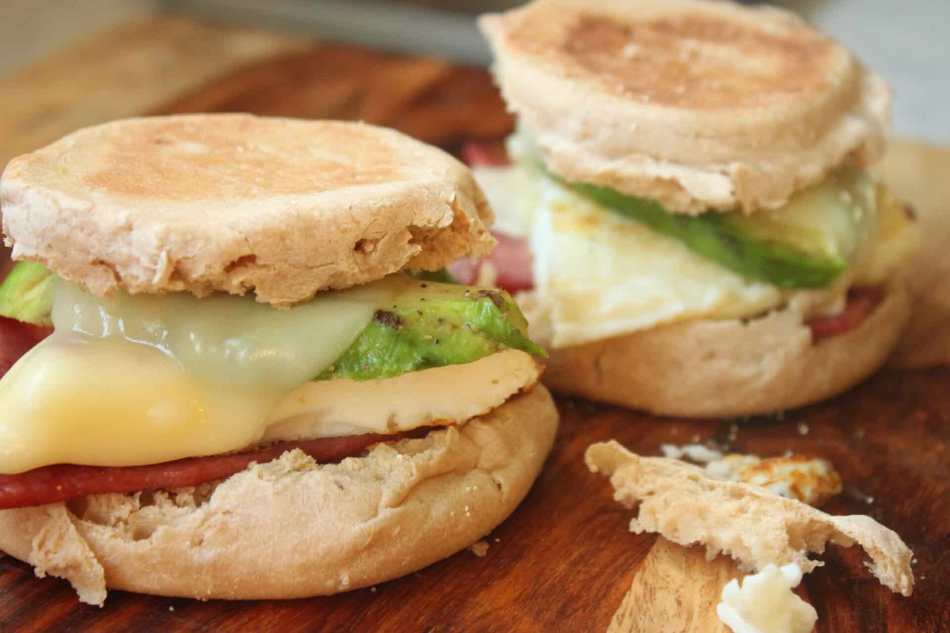 Delicious avocado and turkey bacon breakfast sandwiches on a rustic table, stacked high with egg whites, avocado, and melty cheese.