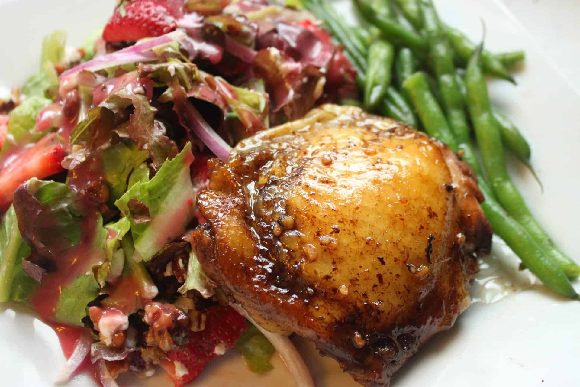 Flavor-Packed Baked Balsamic Chicken Thighs You Can Make Tonight 9 A plate of baked balsamic chicken thighs served with salad and green beans, highlighting a flavorful and easy dinner recipe.