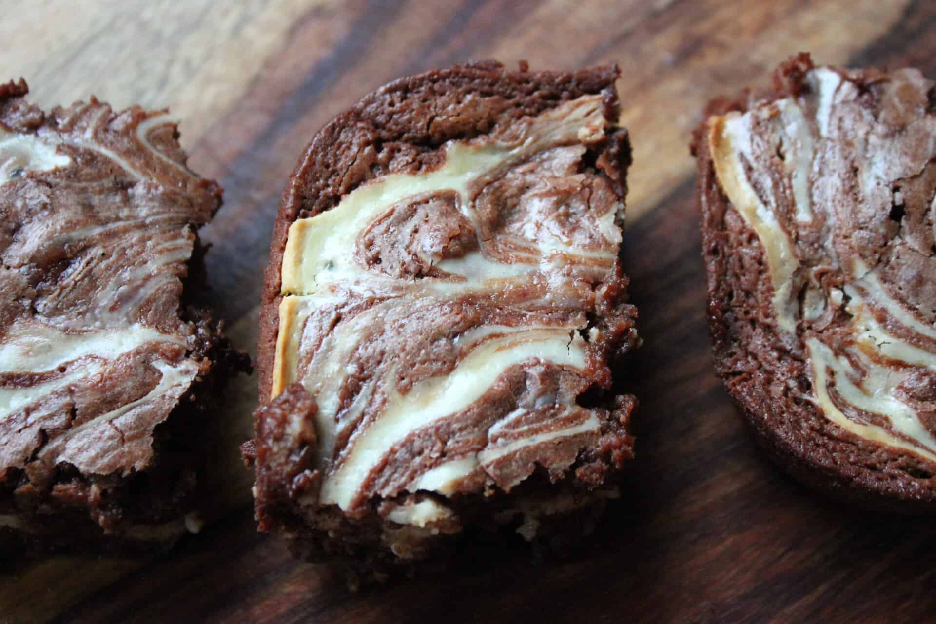 Two slices of chocolate fudge cream cheese brownies with a rich chocolate layer and a swirled cream cheese filling on top.