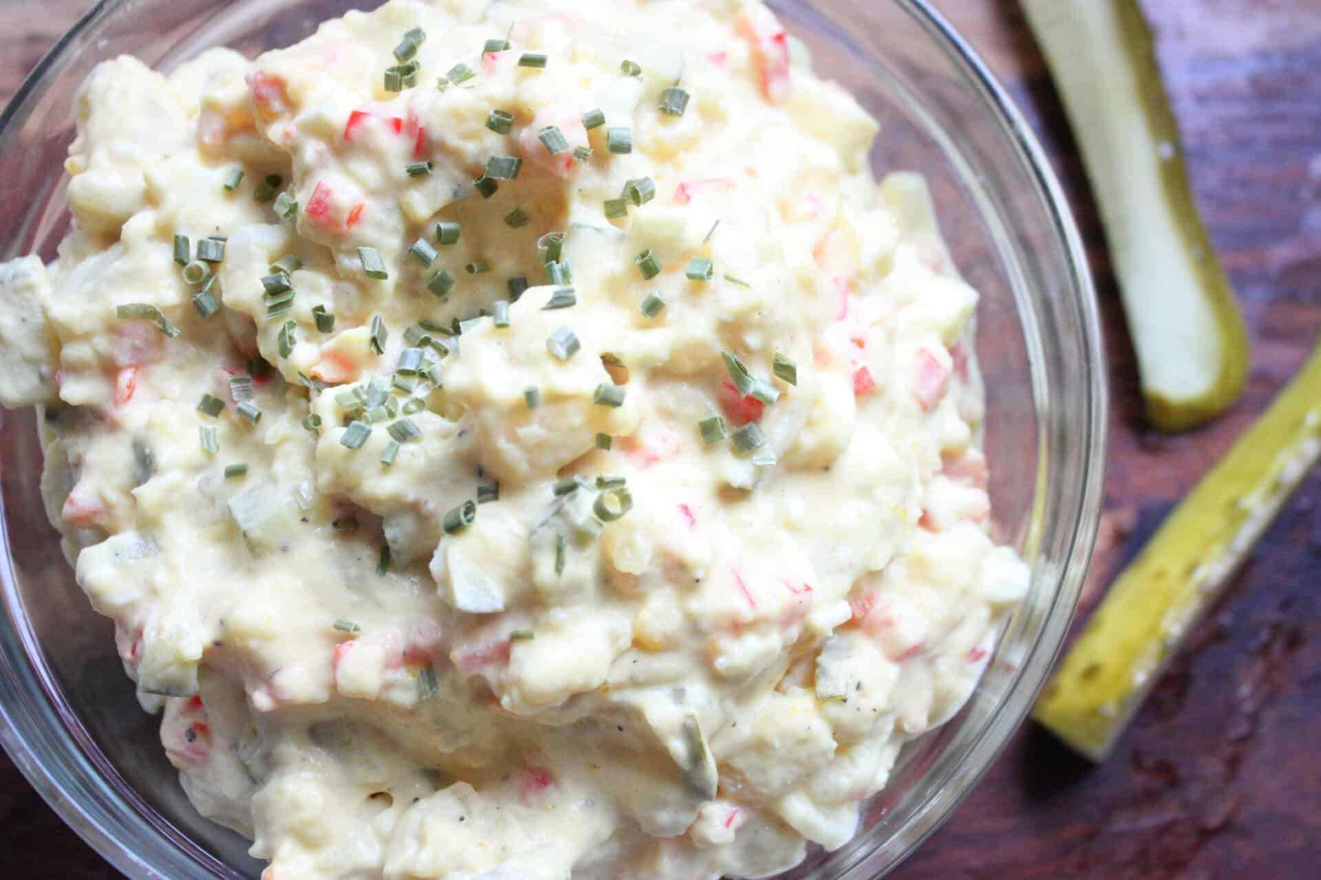 A close-up of Grandma Ruth’s chunky potato salad showing chunky potatoes, eggs, pickles, and creamy dressing in a large bowl.