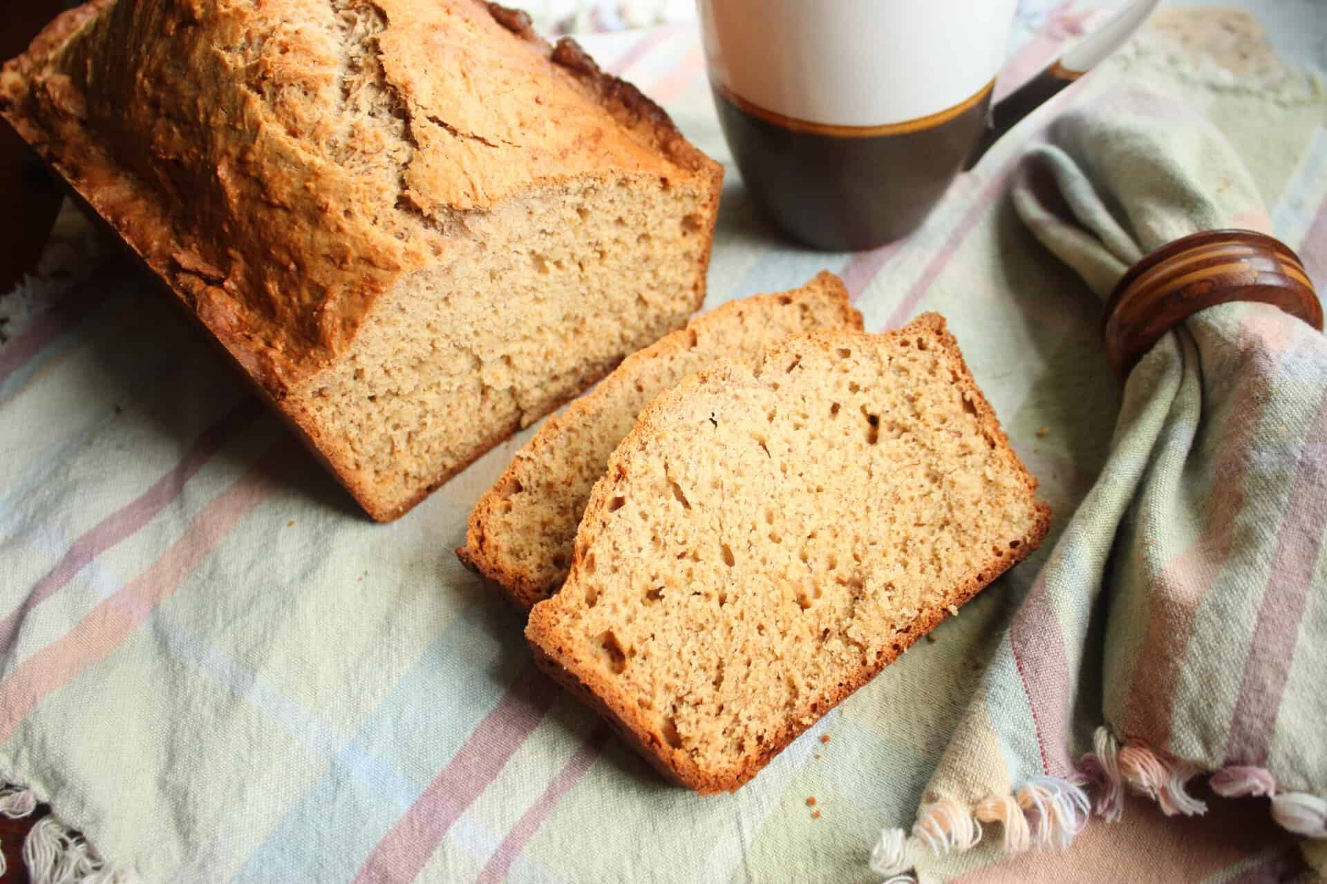 Fast and Foolproof 3-Step Easy Banana Bread Recipe for Busy Bakers 10 Sliced easy banana bread on a cozy table with a mug of coffee, highlighting the moist texture and light brown color of each slice.