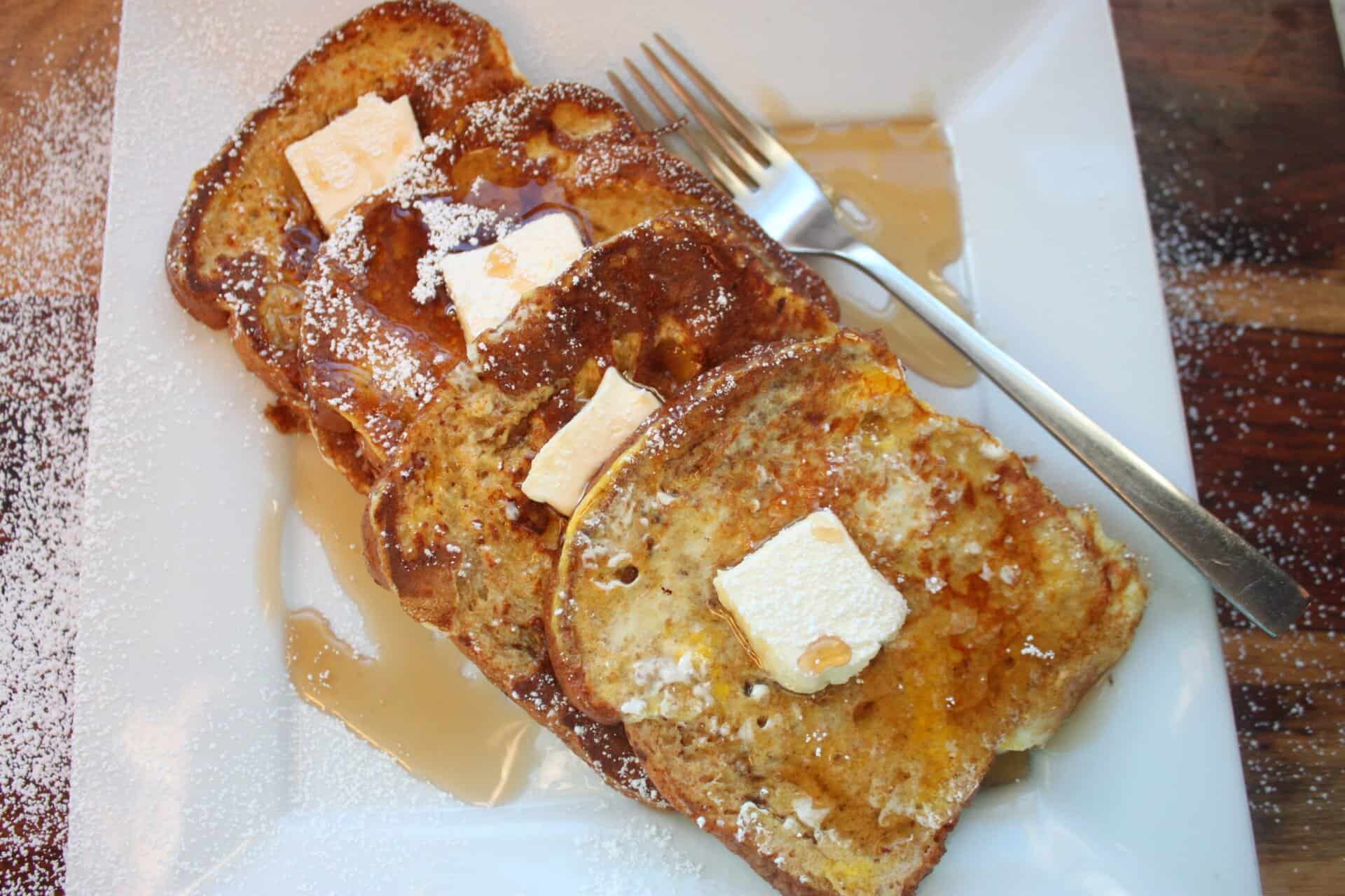 Plated Easy Cinnamon French Toast topped with butter and syrup, with a fork beside it ready for breakfast.