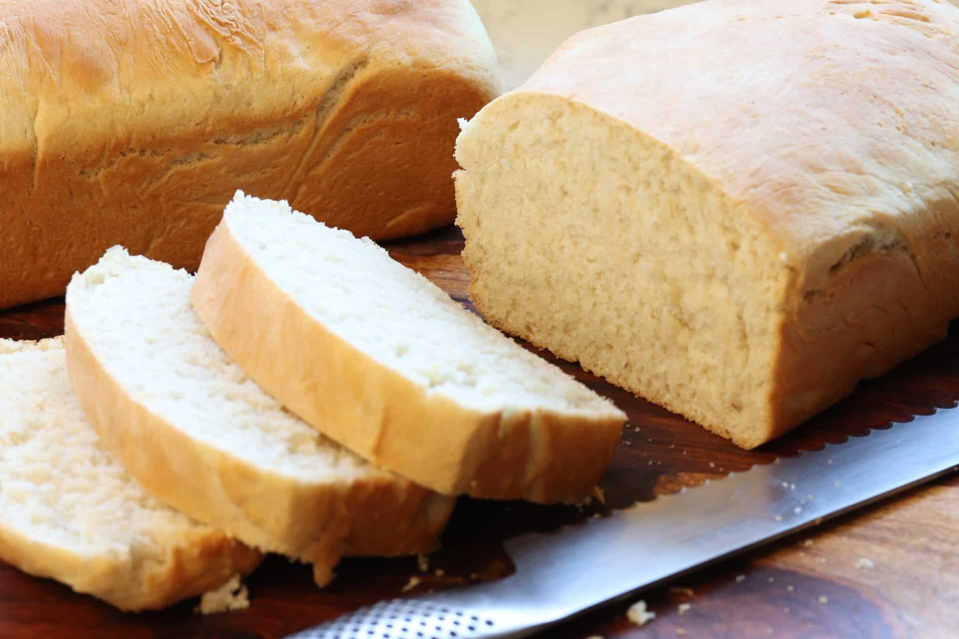 Golden loaves and thick slices of Easy Homemade Bread on a wooden board, ready to enjoy with butter, jam, or alongside a warm meal.