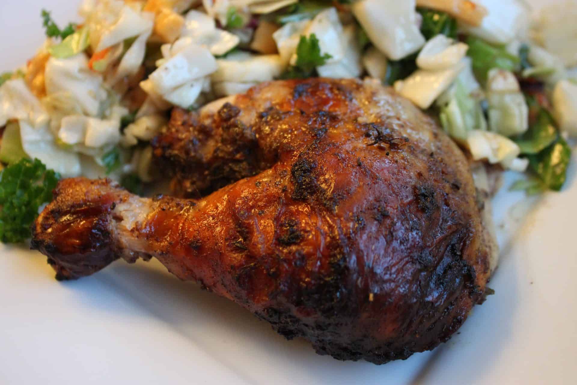 A roasted whole chicken with a golden, crispy skin resting on a bed of fresh chopped vegetables for Easy Roasted Jerk Chicken.