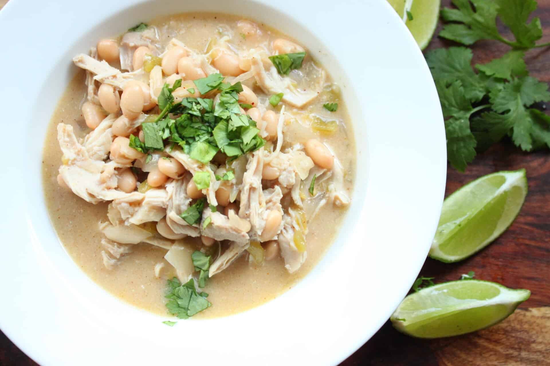 Try This Family-Favorite Healthy Crockpot White Chicken Chili Recipe 12 Close-up of a creamy bowl of Healthy Crockpot White Chicken Chili filled with shredded chicken, beans, and green chiles.