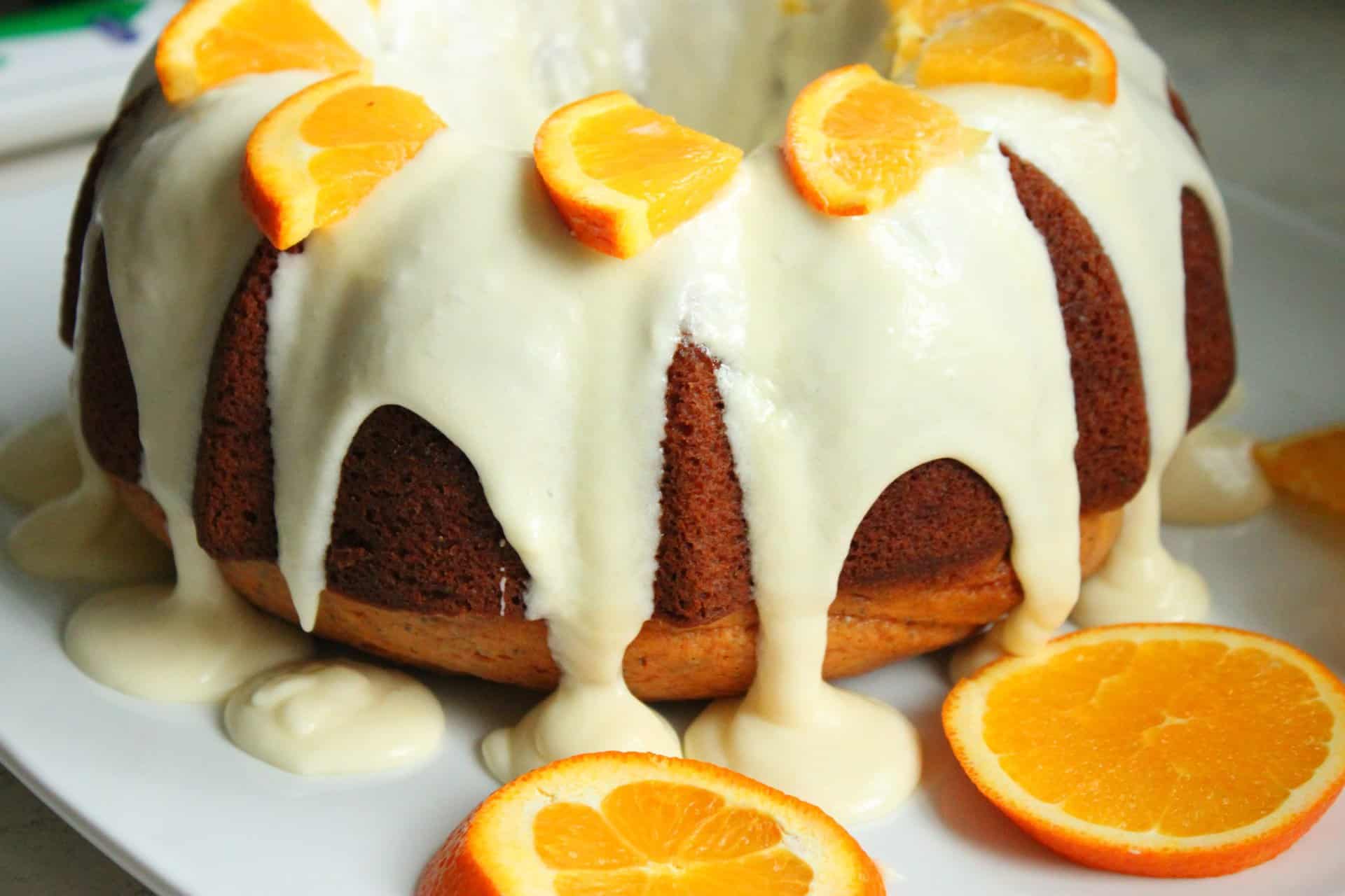 How to Make the Perfect Orange Poppy Seed Bundt Cake for Brunch 14 Whole Orange Poppy Seed Bundt Cake topped with orange glaze and fresh orange slices, ready to serve on a bright white plate.
