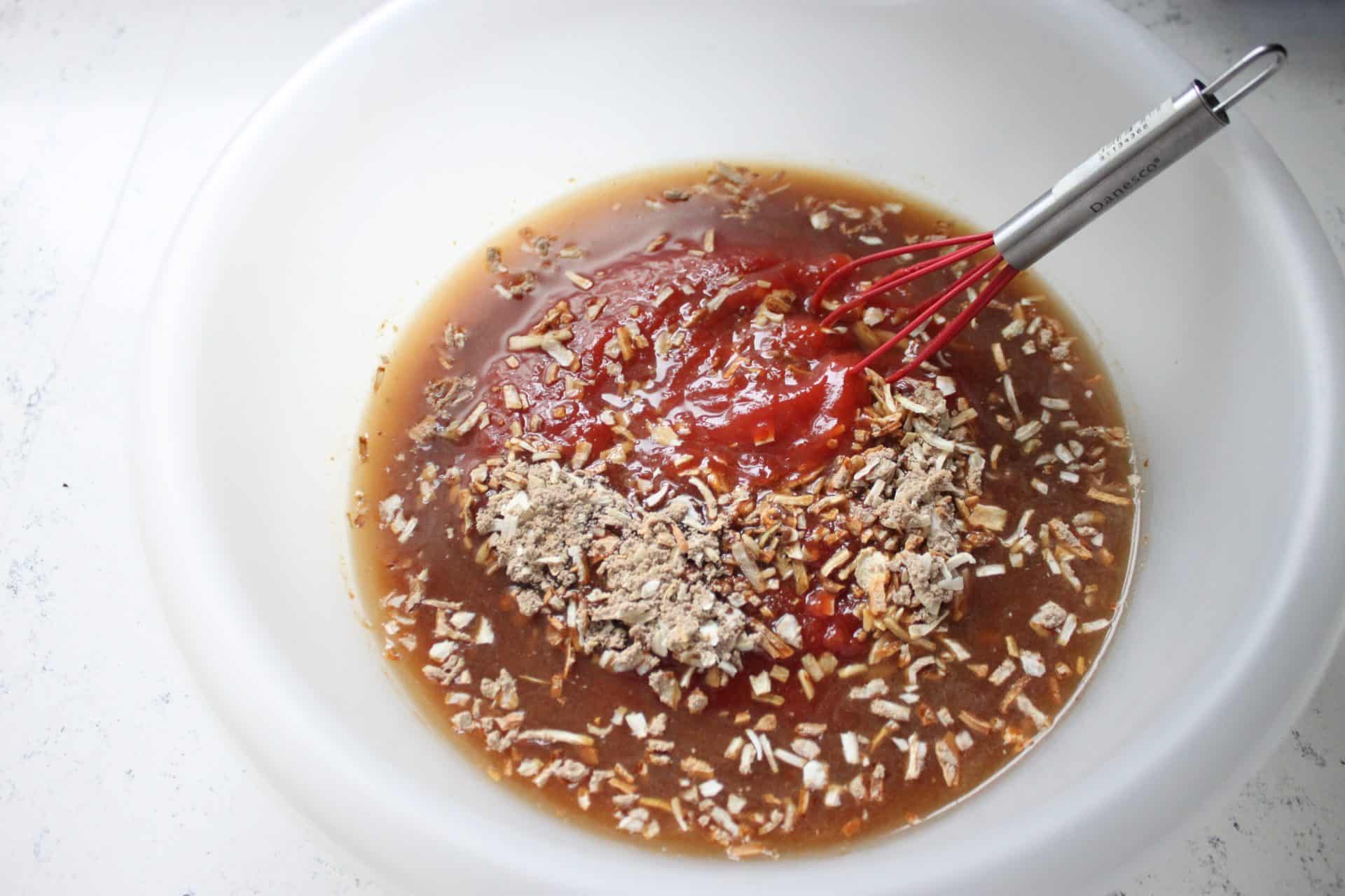 Irresistible 4-Ingredient Slow Cooked Chuck Roast for Easy Dinners 1 Ketchup, Onion Soup Mix, and Water Mixed in a Lage Plastic Bowl with a Whisk