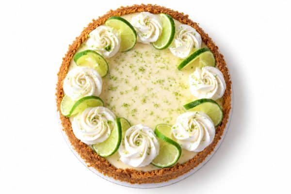 Key lime pie with graham cracker crust, whipped cream, lime slices, and lime zest viewed from overhead