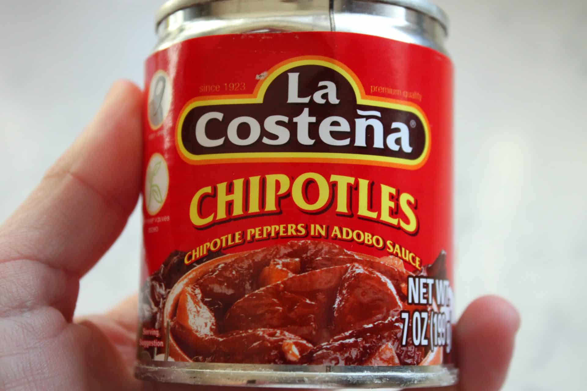 A can of La Costeña chipotle peppers in adobo sauce, the key ingredient that gives spicy chicken enchiladas their signature smoky heat.