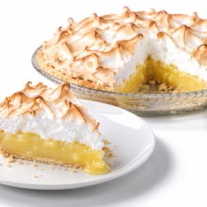 Slice of lemon meringue pie showing yellow lemon filling and meringue, with the pie missing one slice behind it.