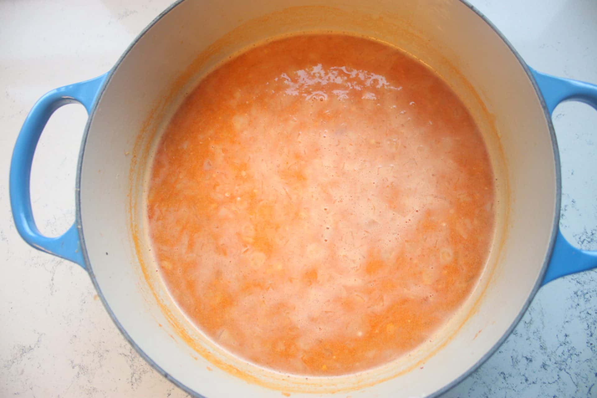 Creamy orange soup base simmering in a pot, forming the velvety foundation of the 30 Minute Dungeness Crab Bisque Recipe.