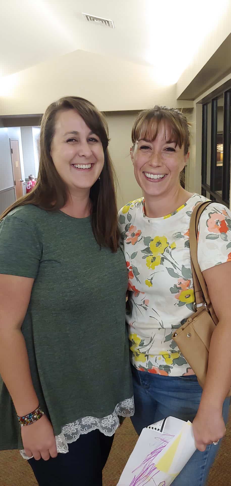 Two smiling women in a well-lit kitchen after finishing a batch of Homemade Canned Apple Pie Filling together during a fun canning day.