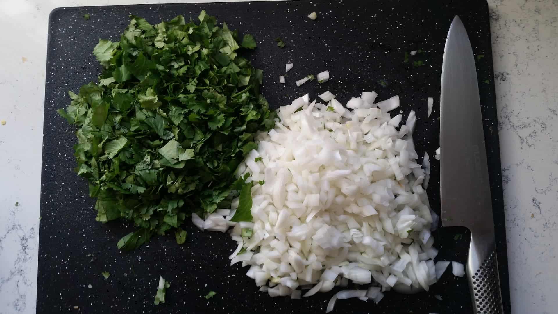 Minced Cilantro and White Onions on a Cutting Board with a Global Chef Knife