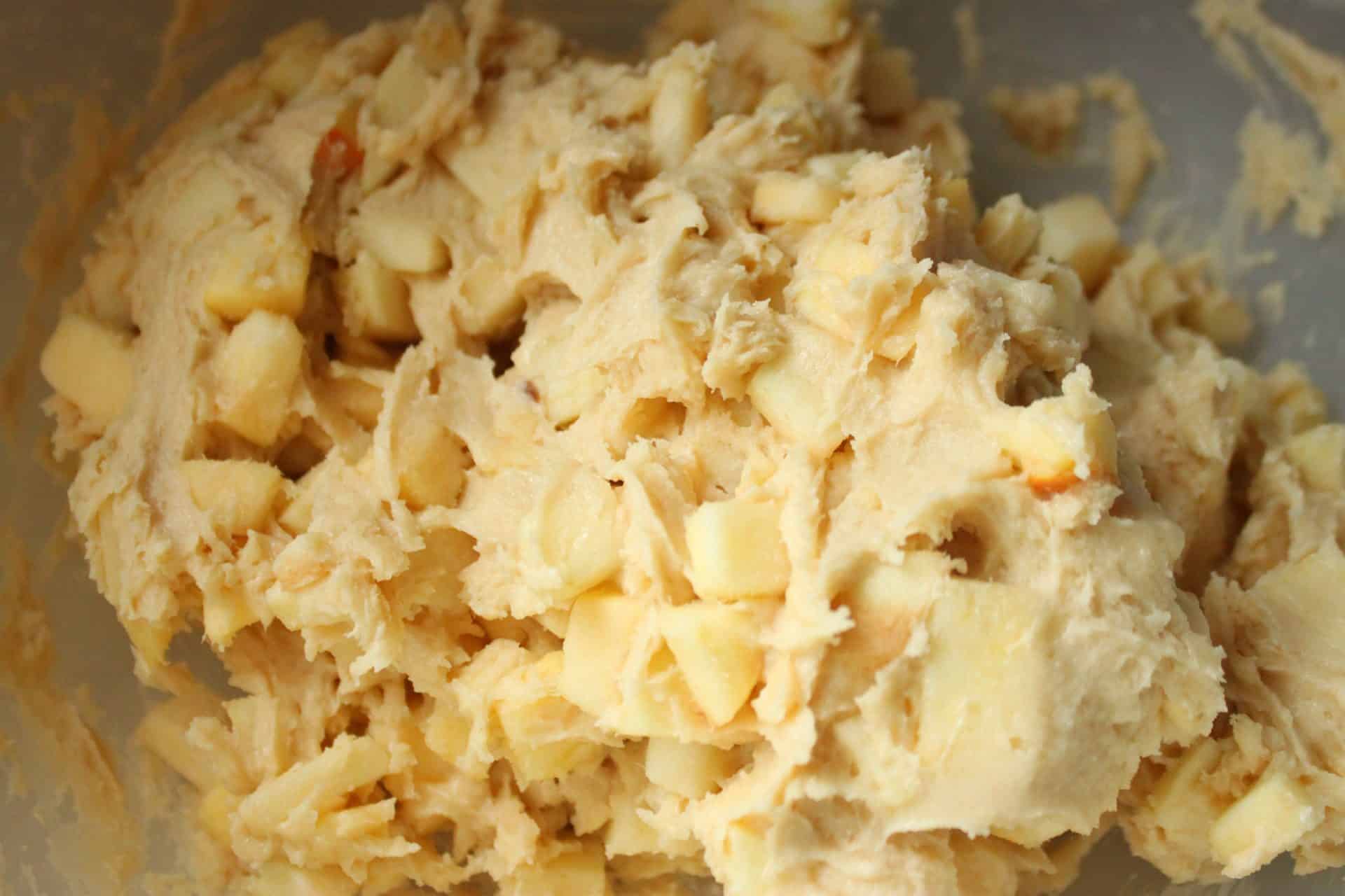 Chunky cinnamon apple muffin batter mixed with fresh apple pieces, ready to be spooned into muffin tins.