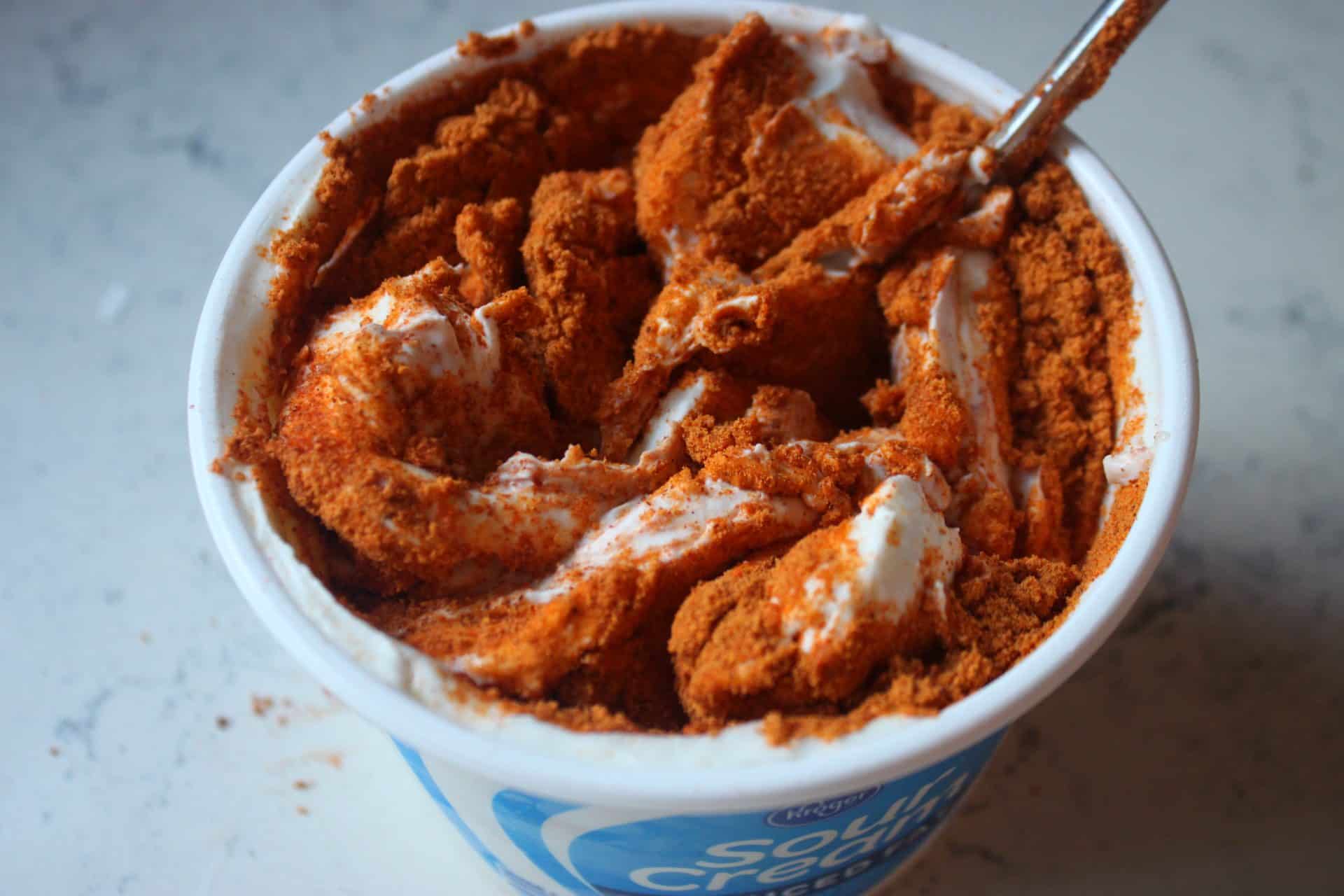 Crowd-Pleasing 7-Layer Mexican Bean Dip for Dinner or Parties 1 Taco seasoning being mixed into sour cream in a white bowl, the second step in creating the flavorful layers of 7 Layer Mexican Bean Dip.