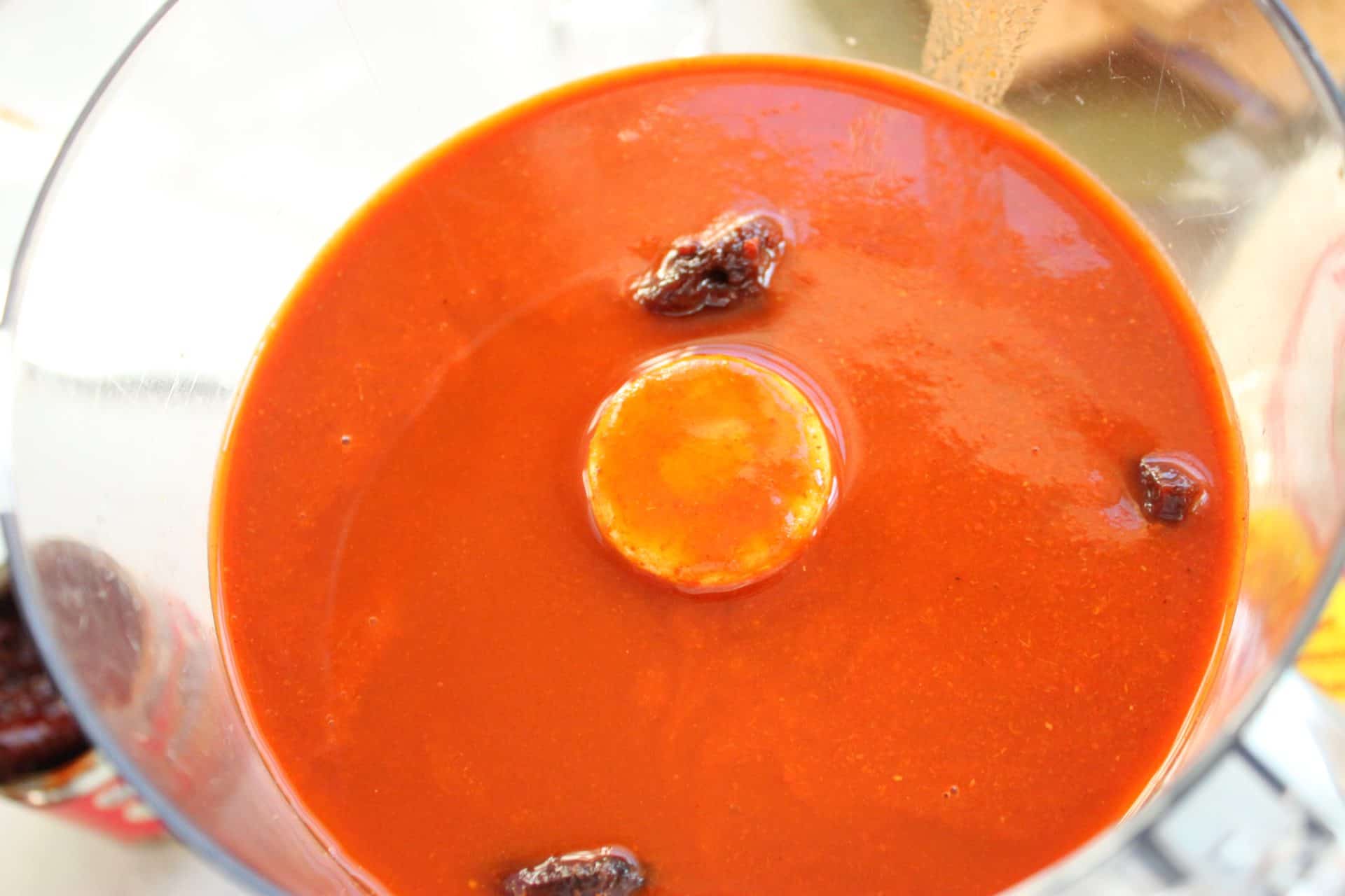 Red enchilada sauce in a blender with chipotles, ready to be blended into a spicy sauce for the spicy chicken enchiladas.