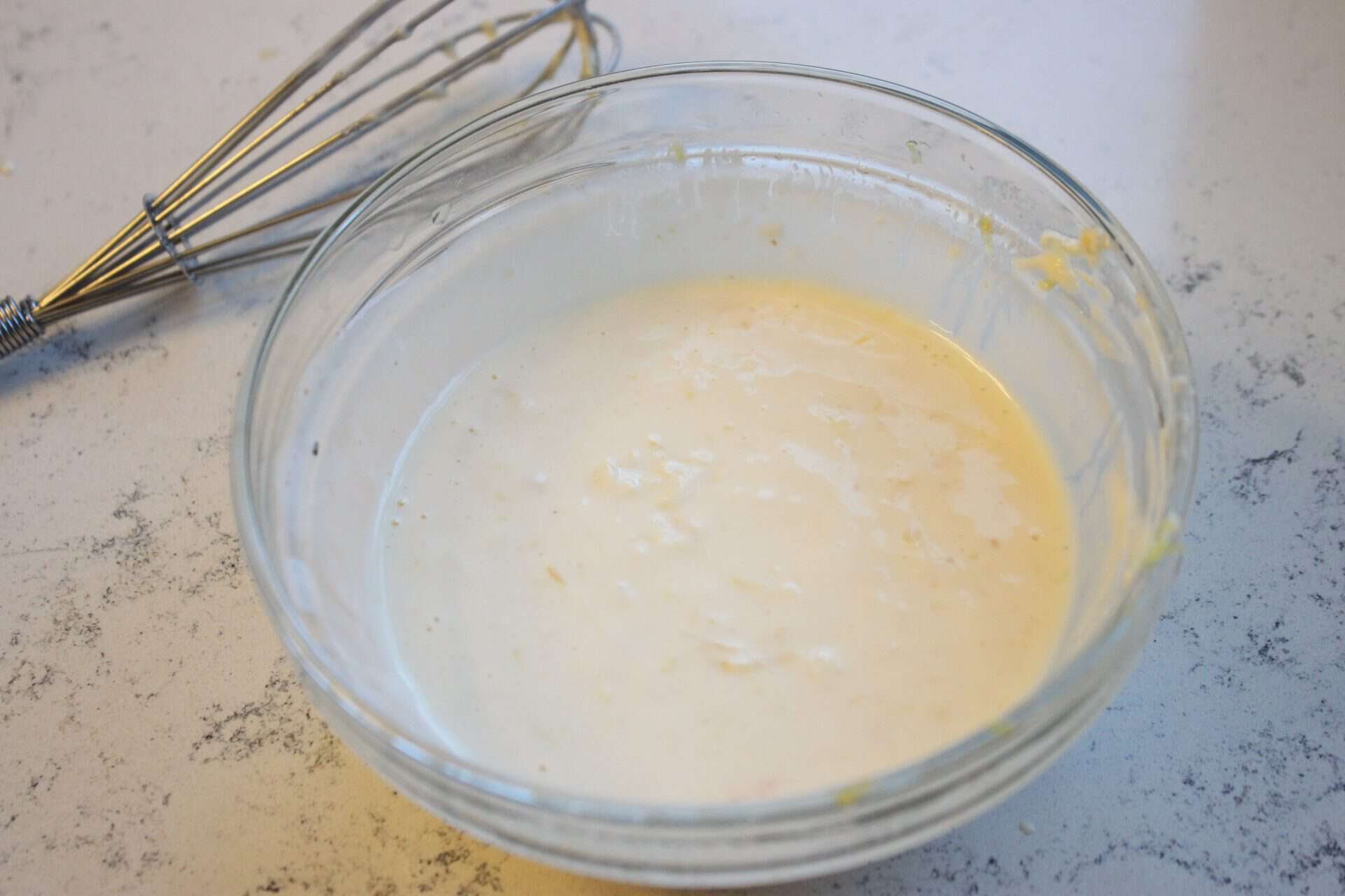 Mixing Horseradish Dressing with a Whisk in a Large Glass Bowl