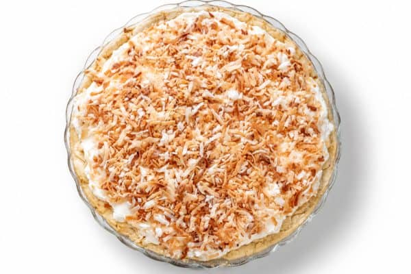Overhead view of coconut cream pie with soft cream topping and a generous layer of coconut shavings.