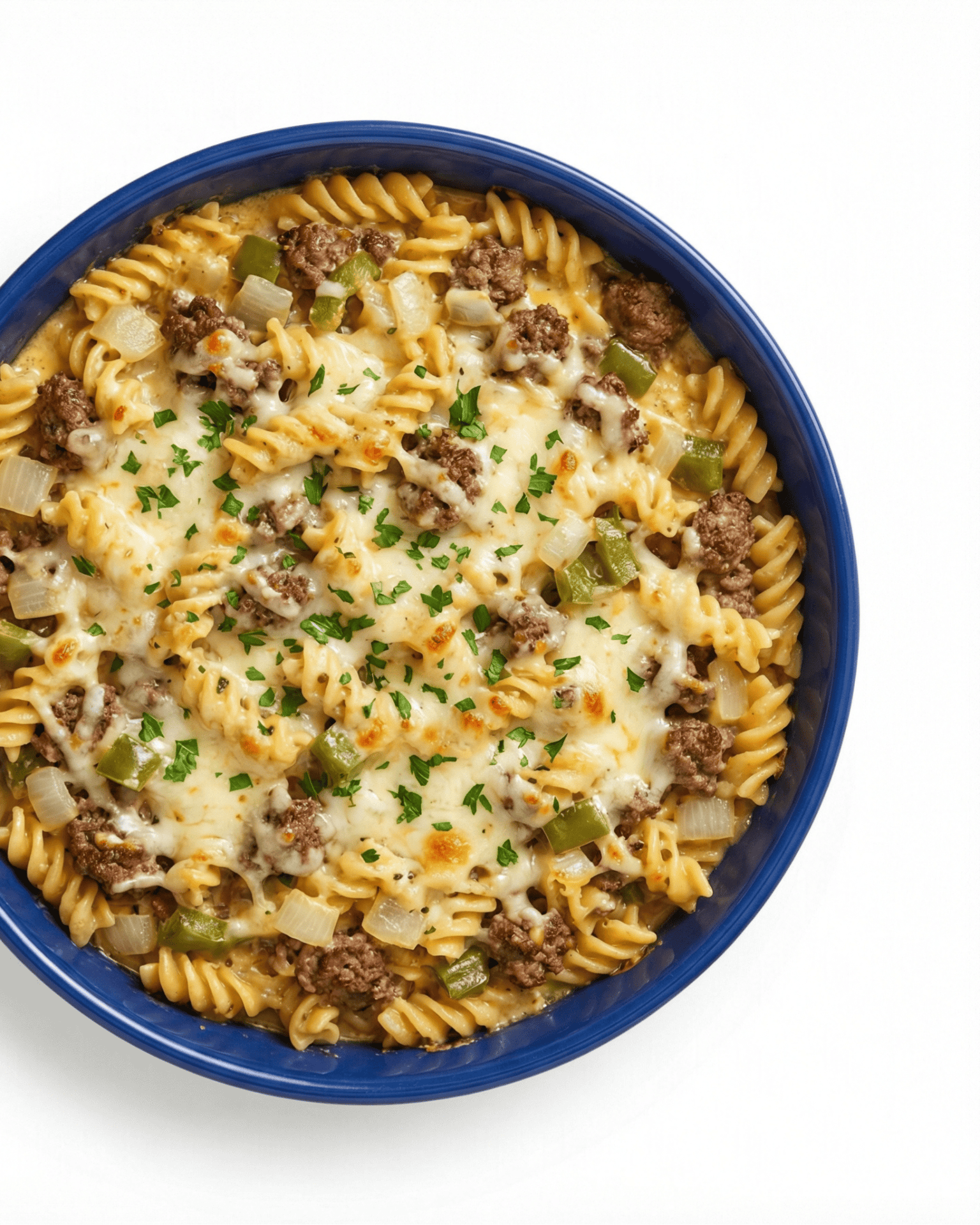 Philly cheesesteak pasta casserole with ground beef, melted provolone, peppers, and onions in blue ceramic dish