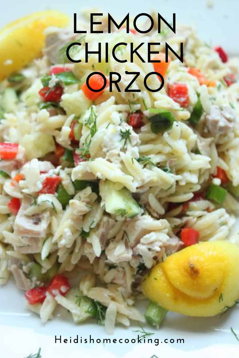 Close-up of lemon chicken orzo salad in a glass bowl with text overlay, showing colorful veggies, chicken, and herbs for a fresh presentation.