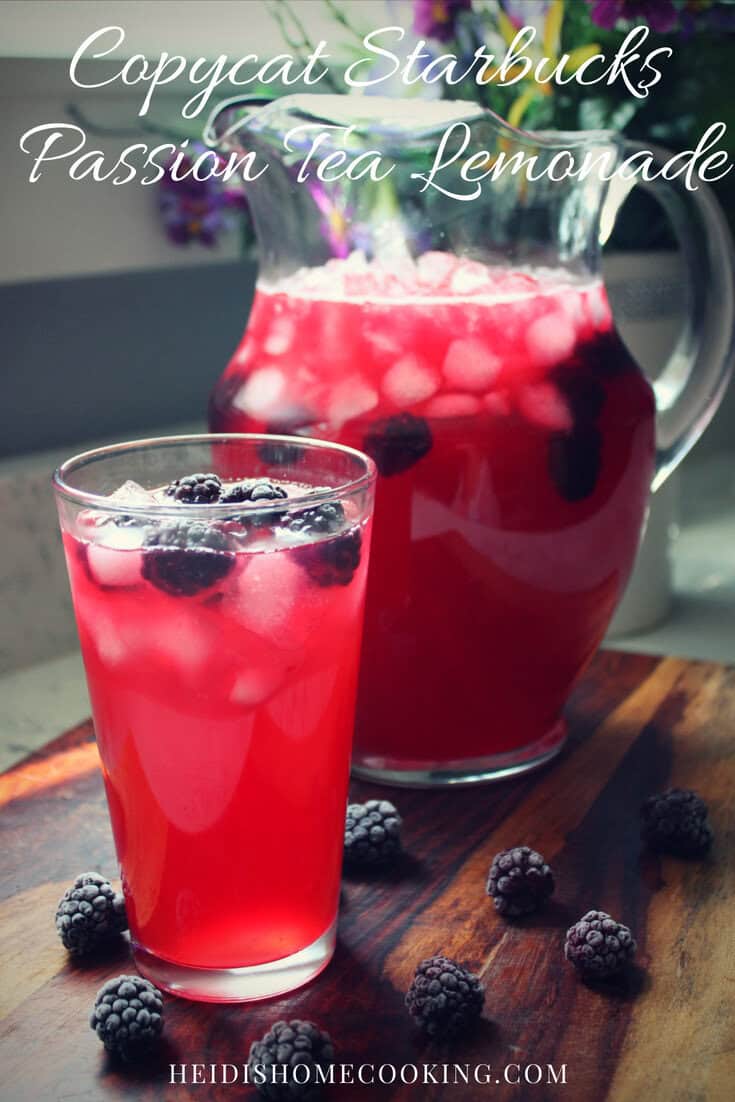 A glass and a pitcher filled with bright pink Starbucks Iced Passion Tea Lemonade, topped with ice and fresh blackberries.